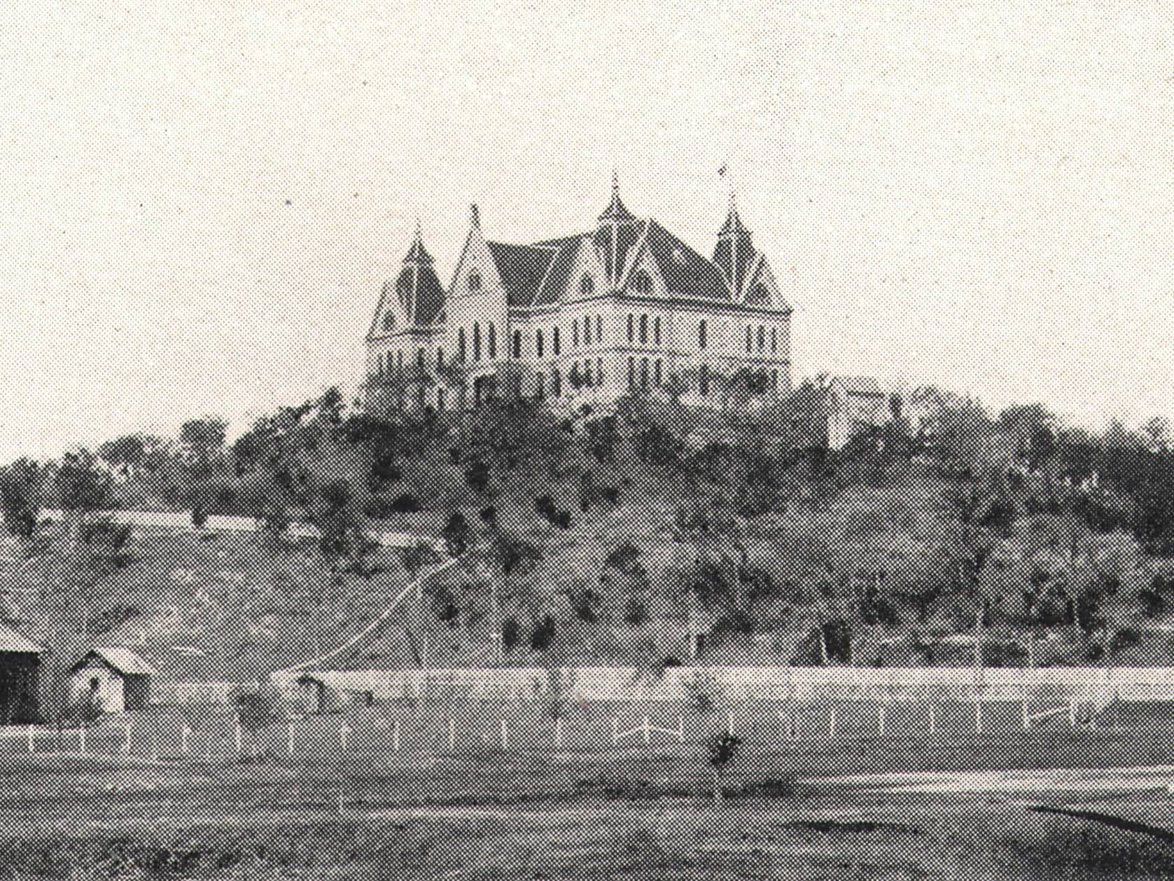 black and white photo of old main on top of hill
