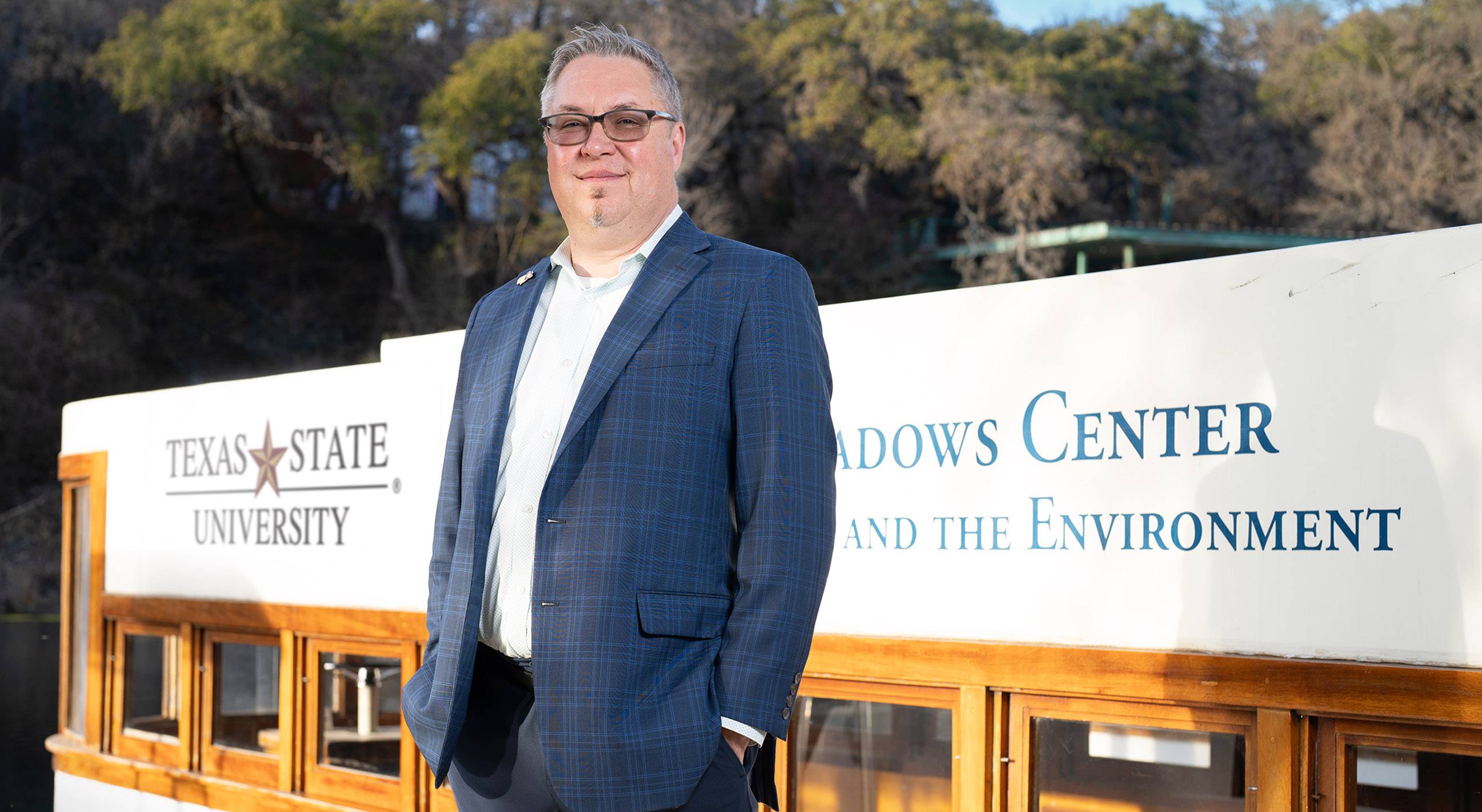robert mace standing in front of glass bottom boat that reads "texas state univeristy / the meadows center" 