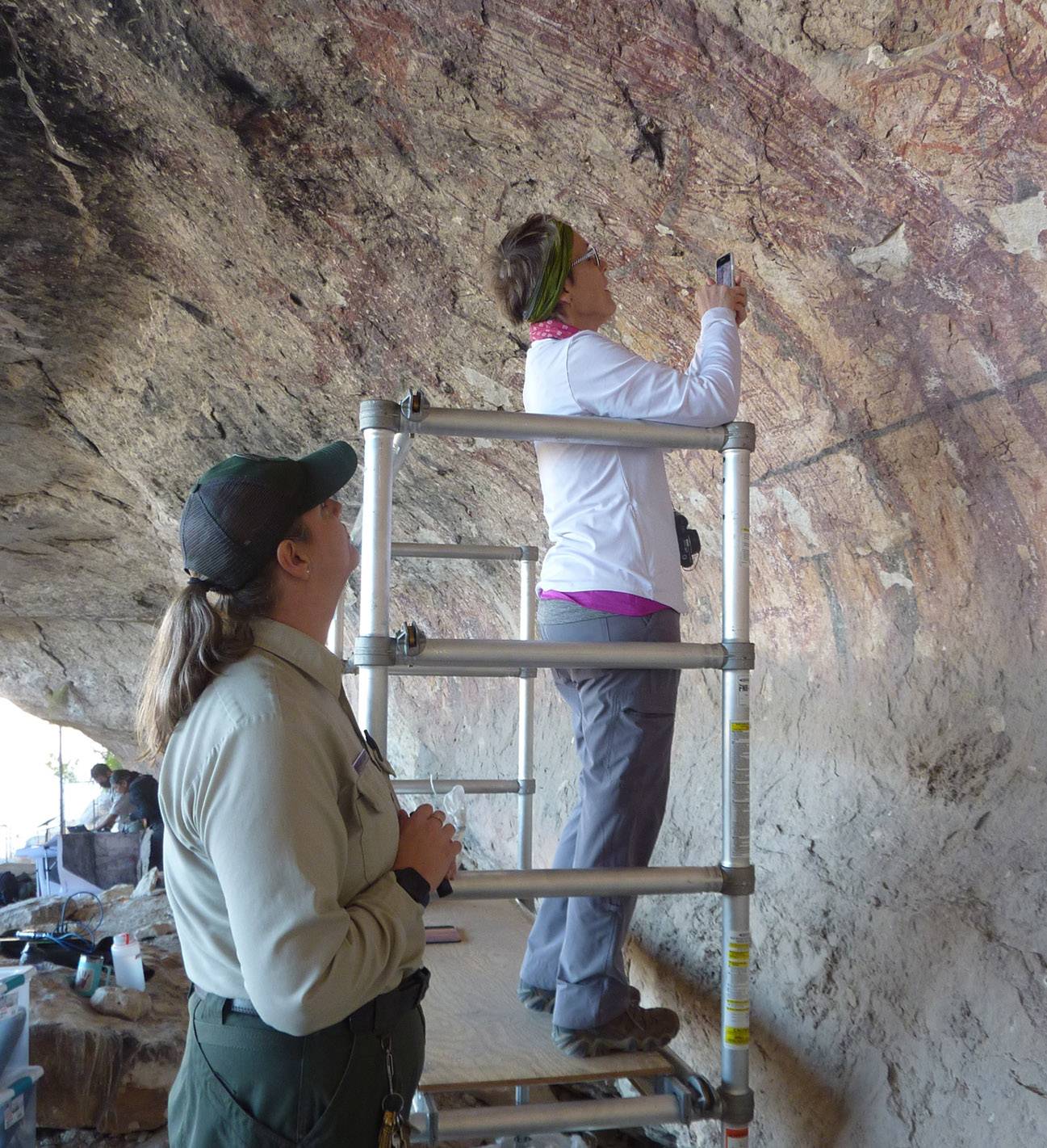 two women working on ancient rock wall