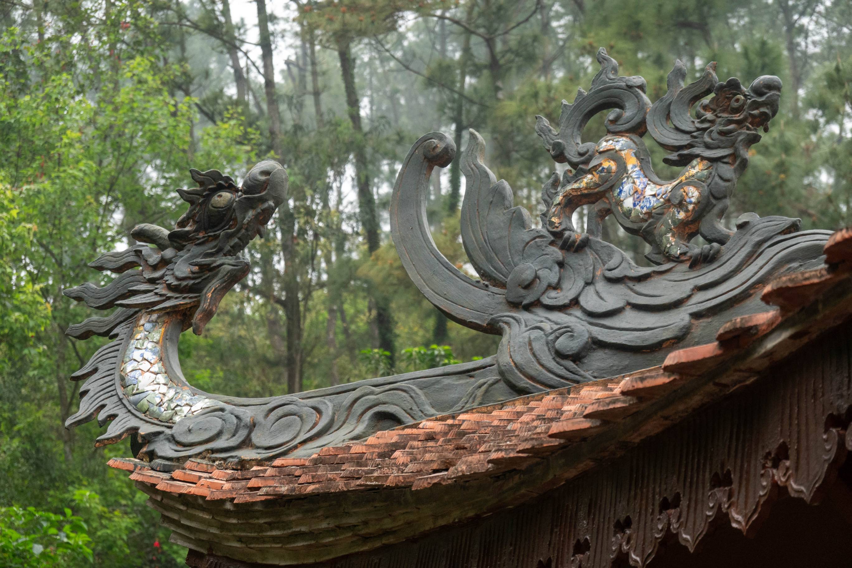 picture of dragon stature (on left) on a rooftop and there is a lion statue on the right