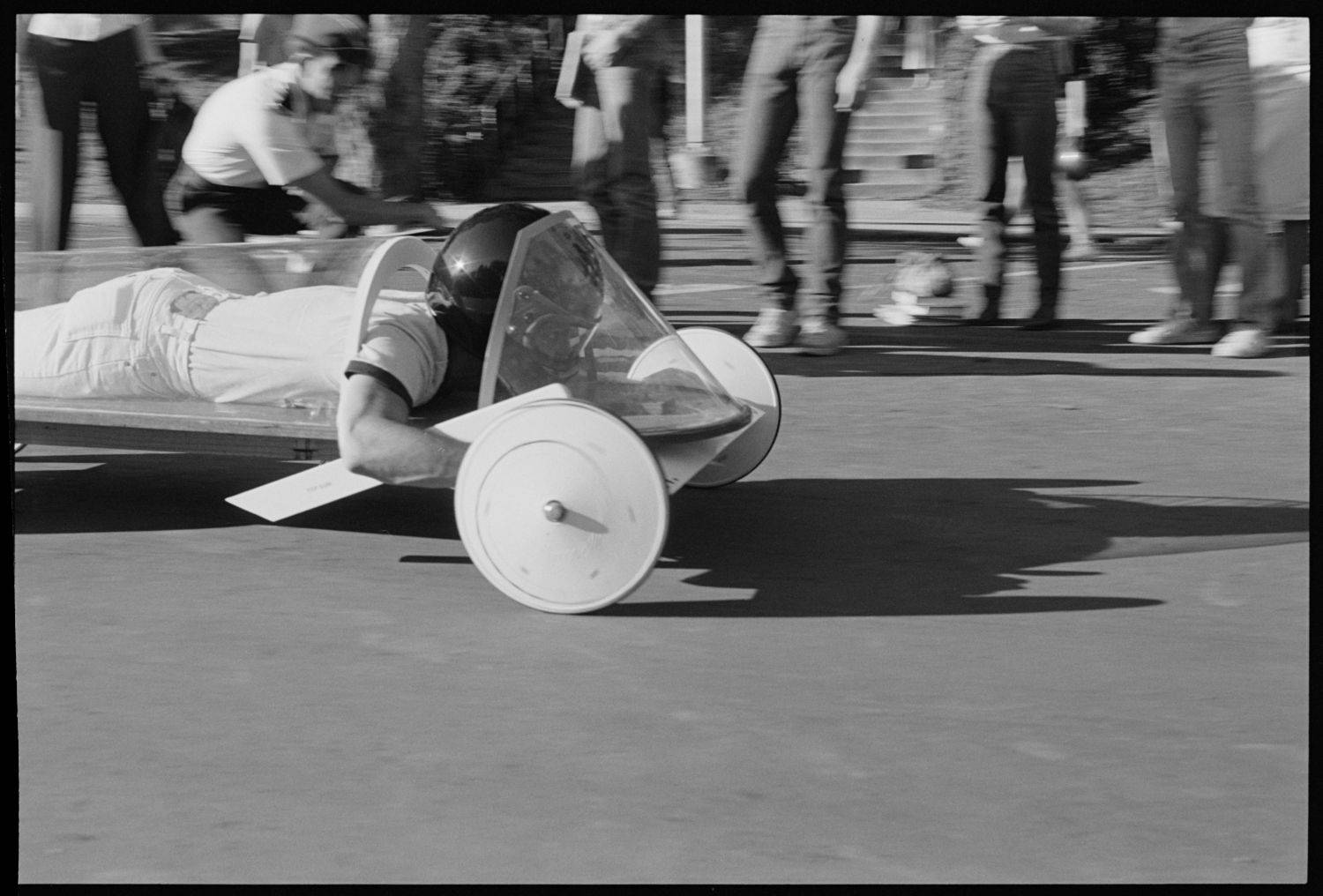 A soap box racer competing stomach down, helmet first. 