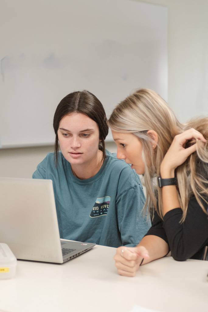 Two Texas State students look at a laptop together.