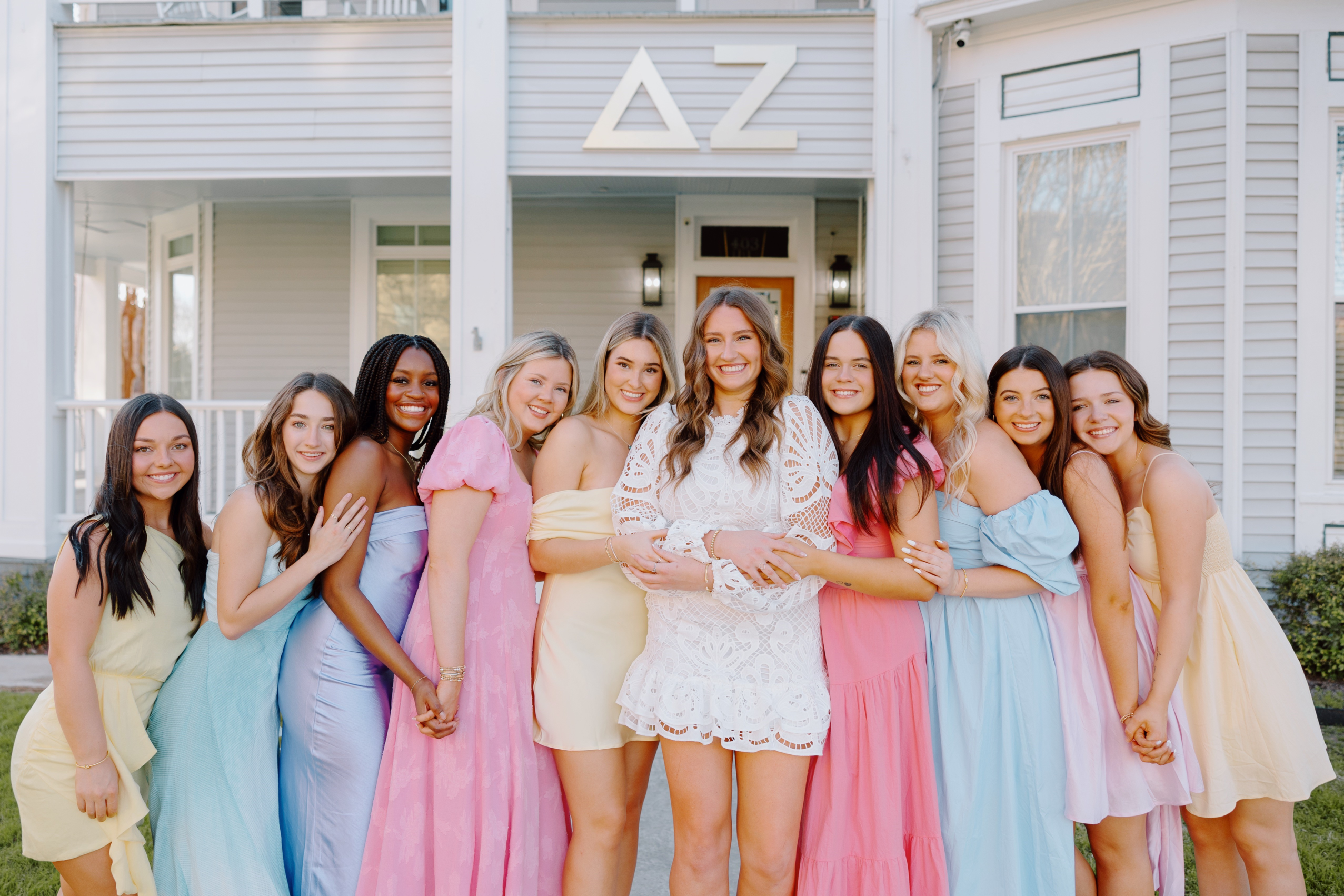 Women of Delta Zeta posing in front of their chapter house