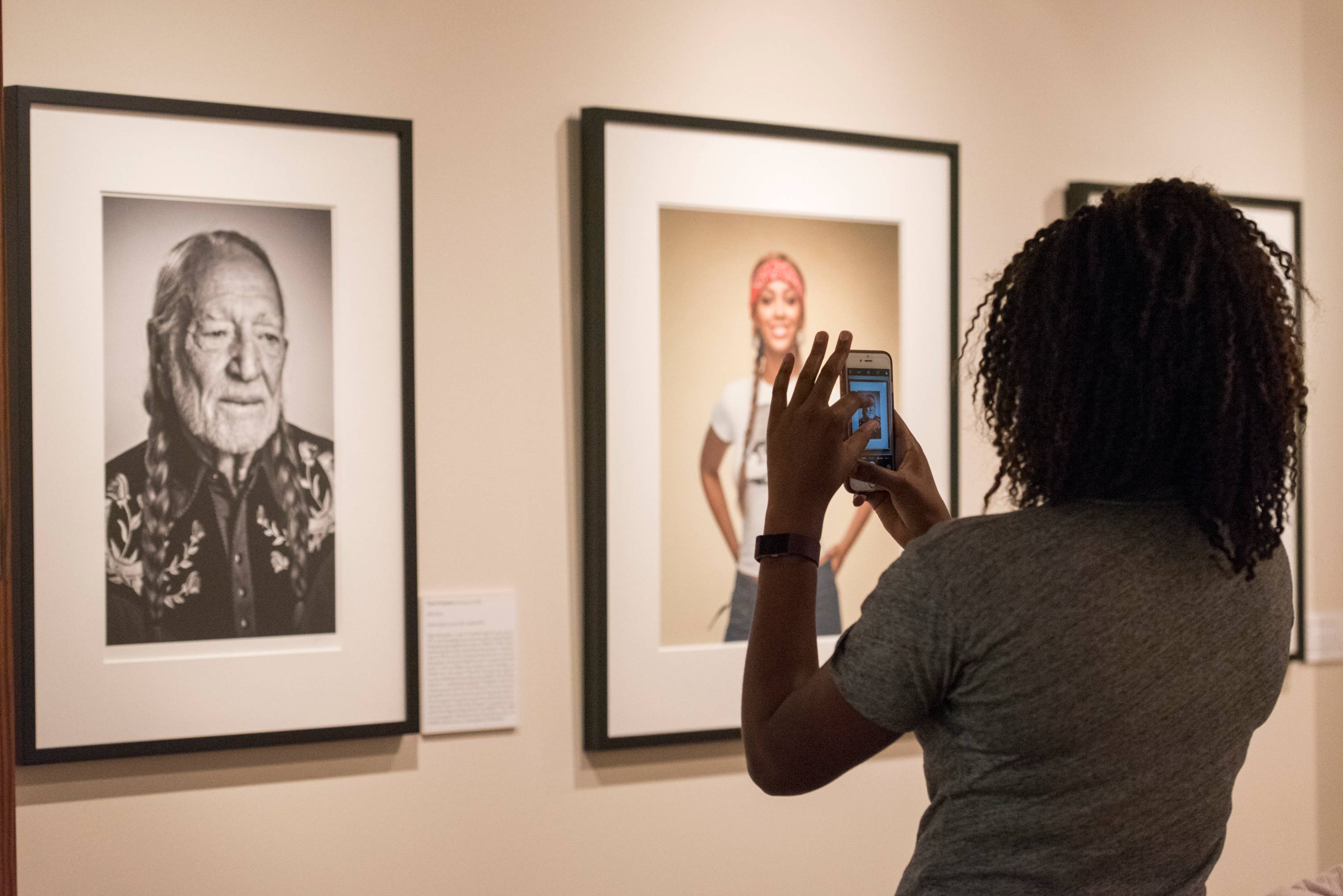 A visitor to the Southwestern Writers Collection captures a photo of a portrait of Texas music legend Willie Nelson.