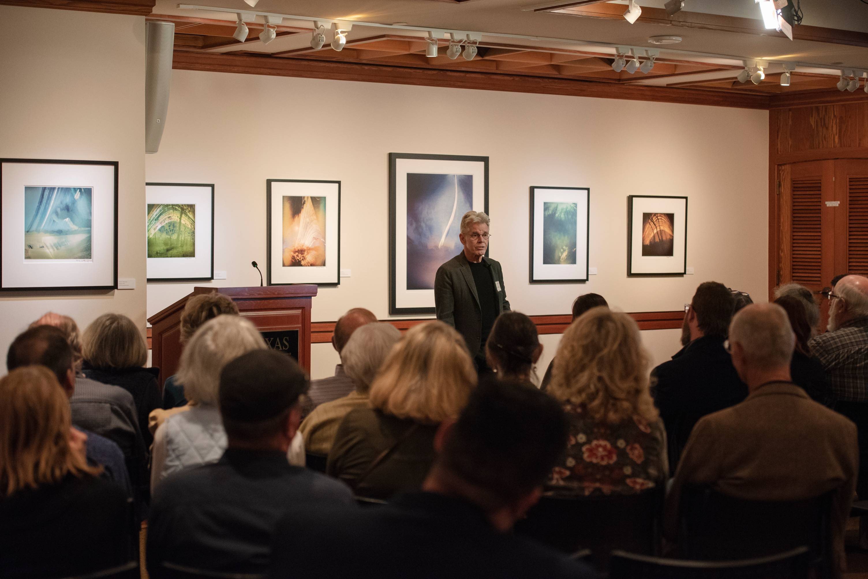  A lecturer stands before a captivated audience with engaging images framed in the background. 