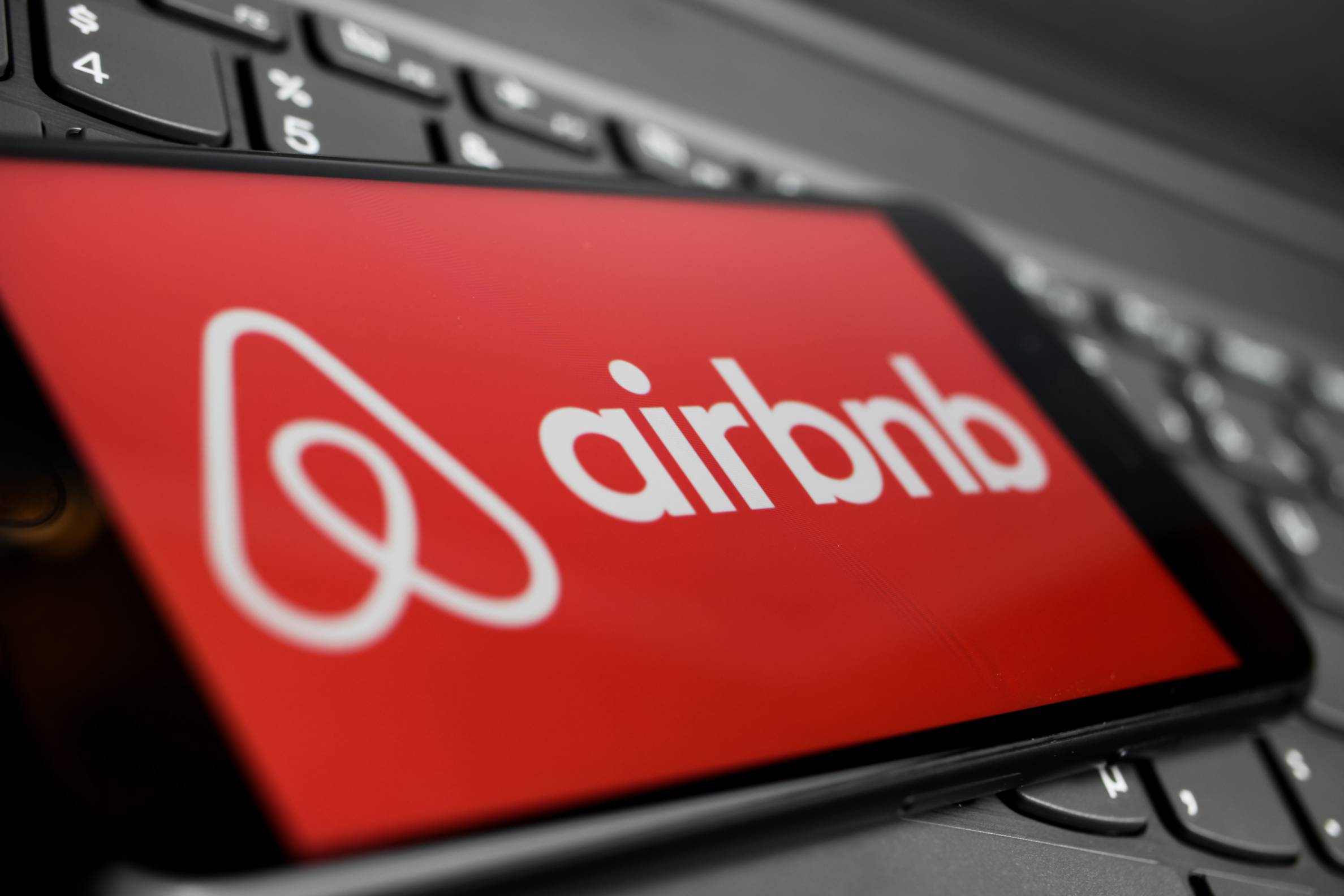 logo for airbnb on a cellphone that is resting on a keyboard