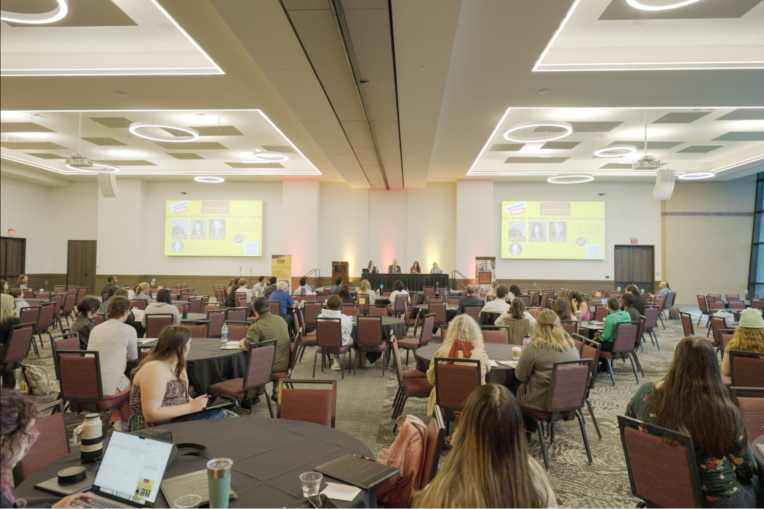 Attendees sitting at tables in front of the STEM conference panel.