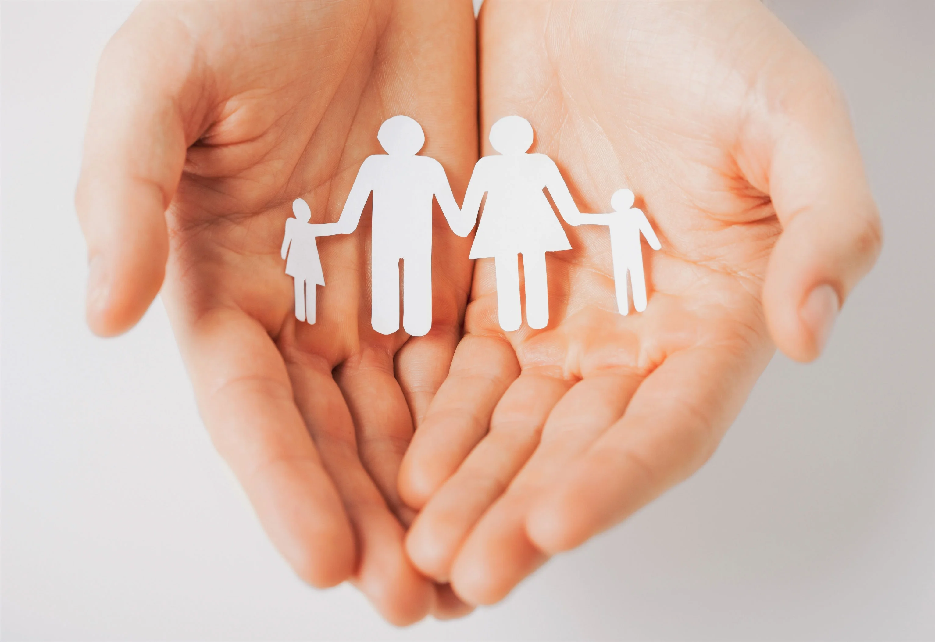 Pair of hands holding a family cut out of paper