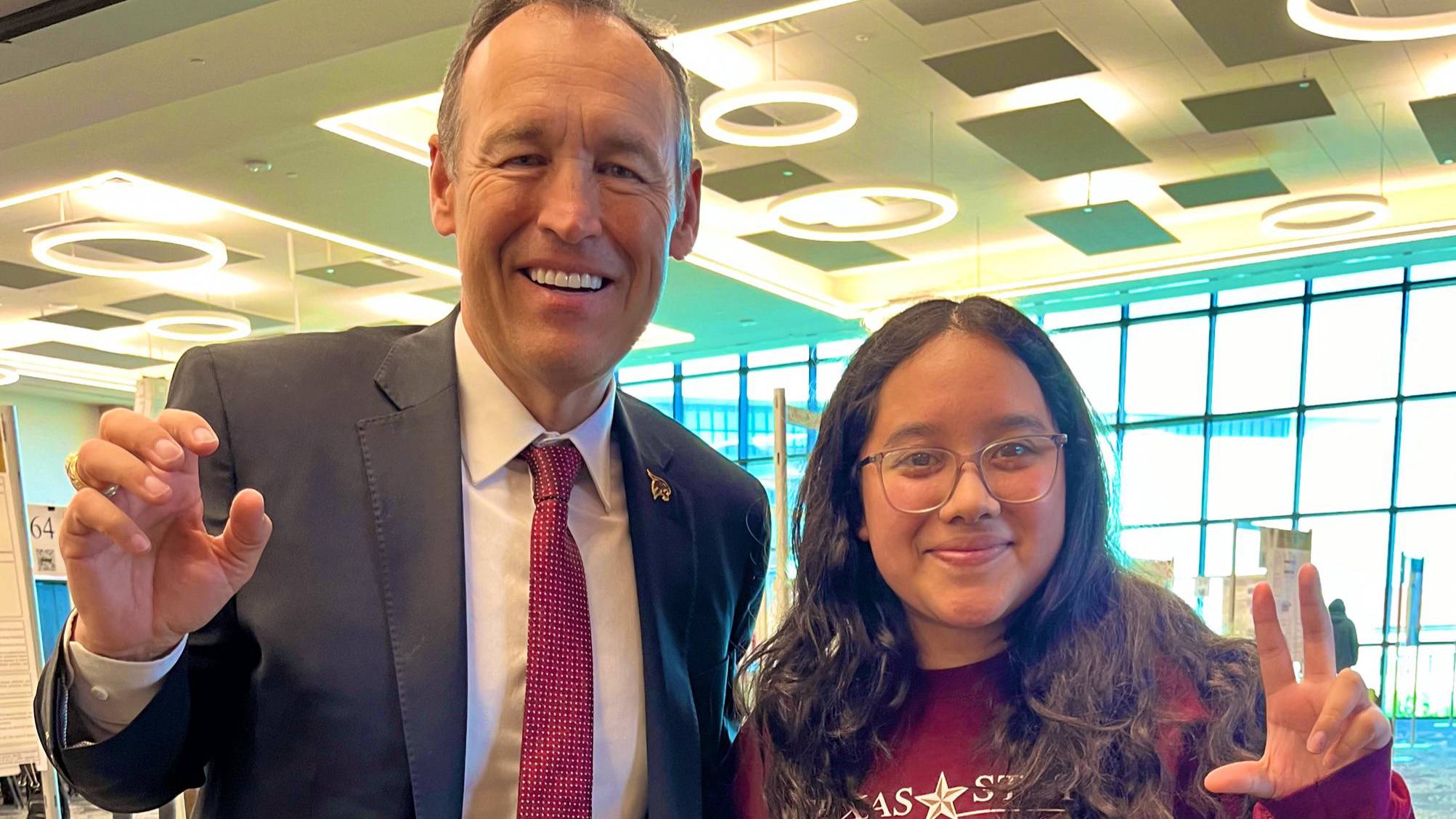 President Damphousse left, pose for a photo with a student.