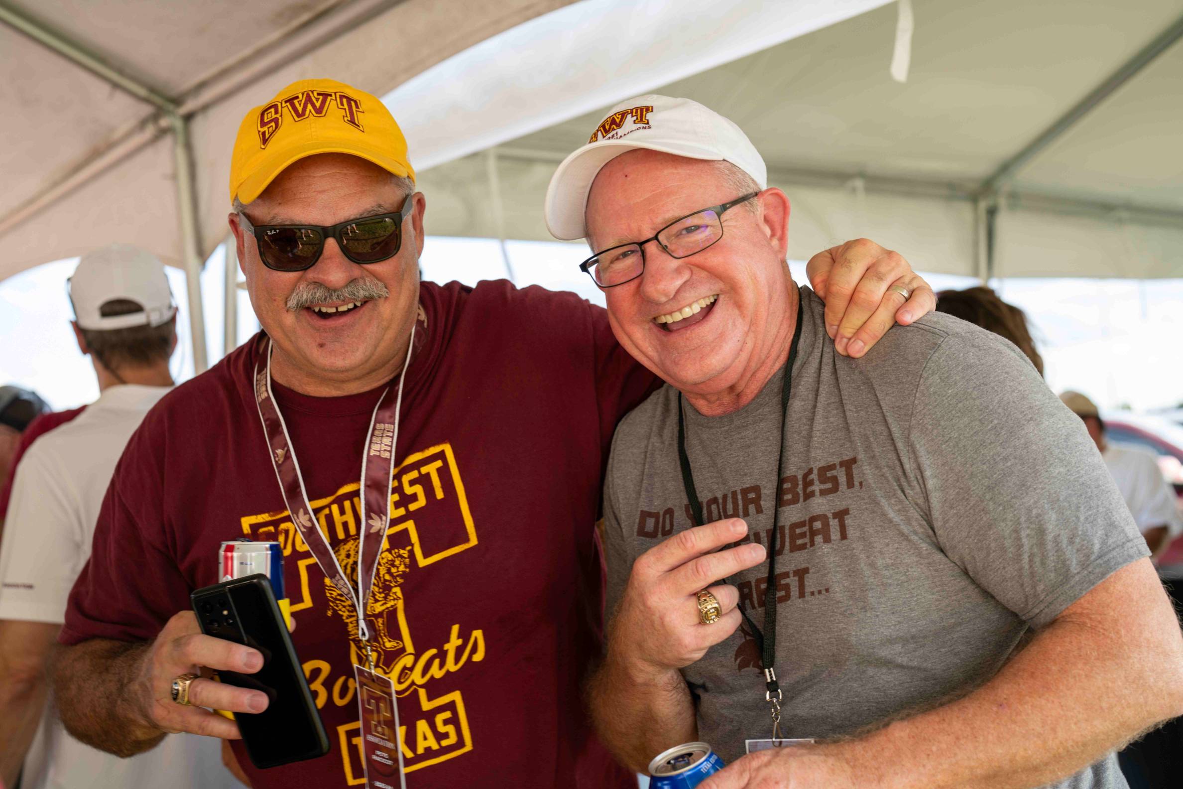 Two men showcasing their school spirit posing together and laughing.