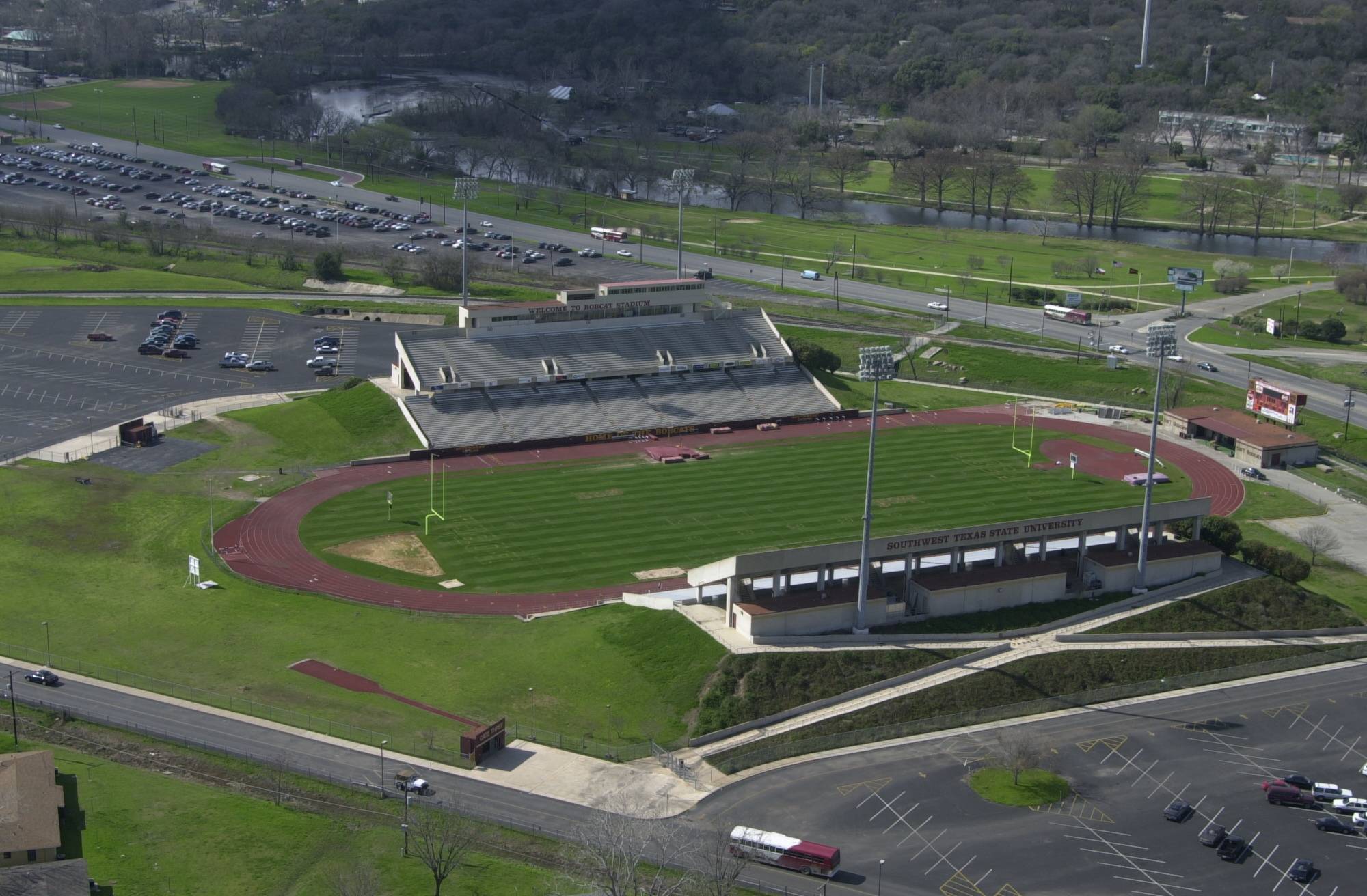 Aerial shot of a grass football field. The area surrounding the field appears to be parking lots and underdeveloped land.