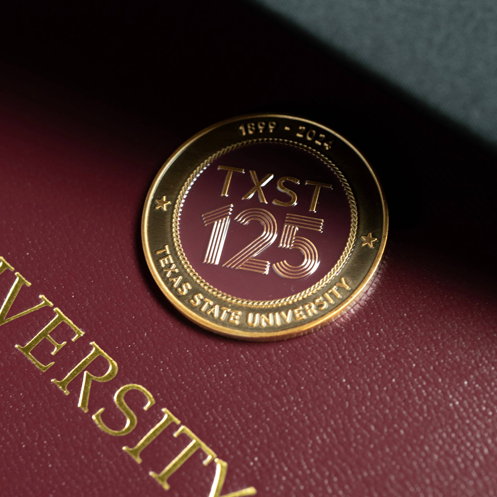 close up of a gold coin that reads "TXST 125"
