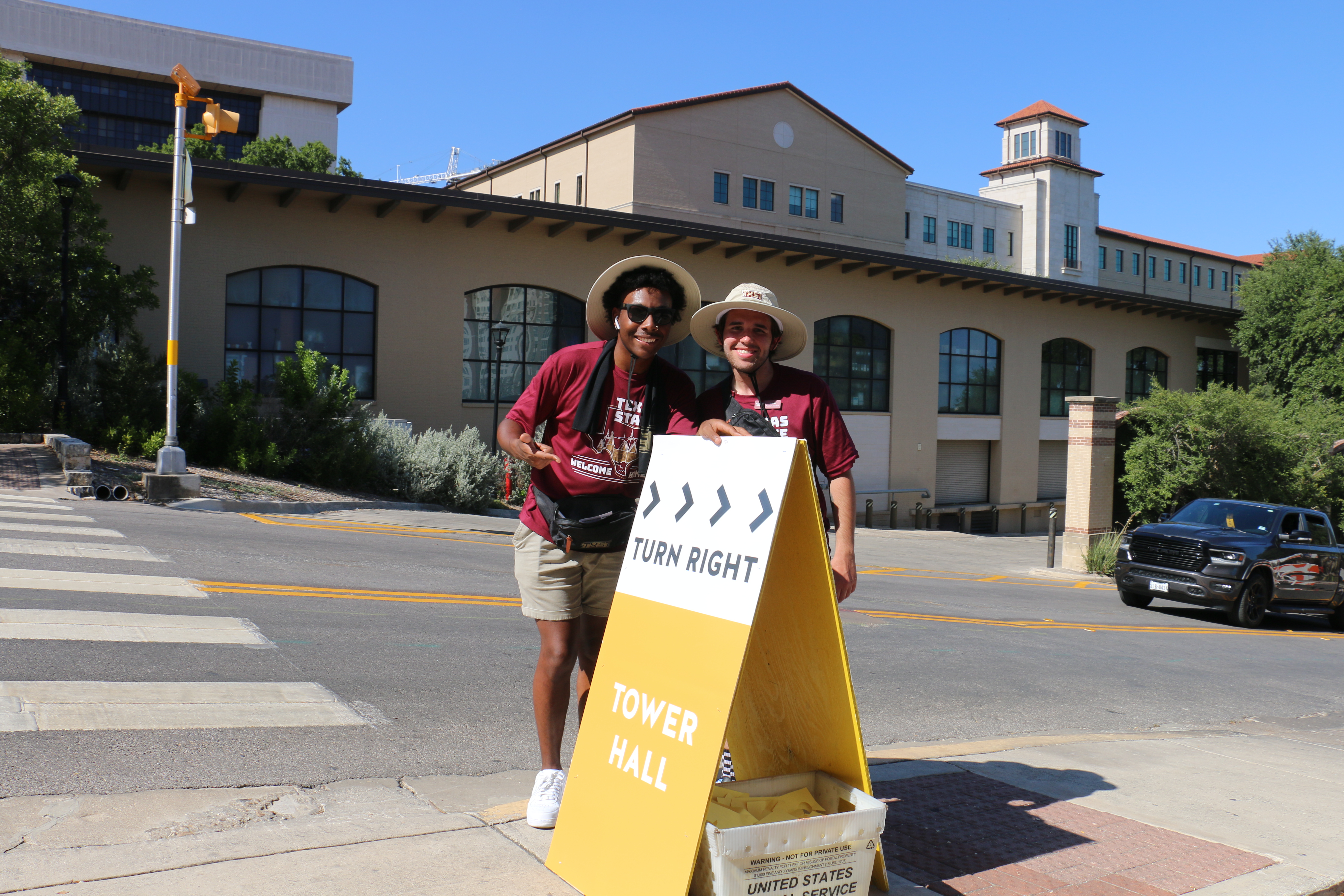 two male RA's standing in front of a tower hall sign 