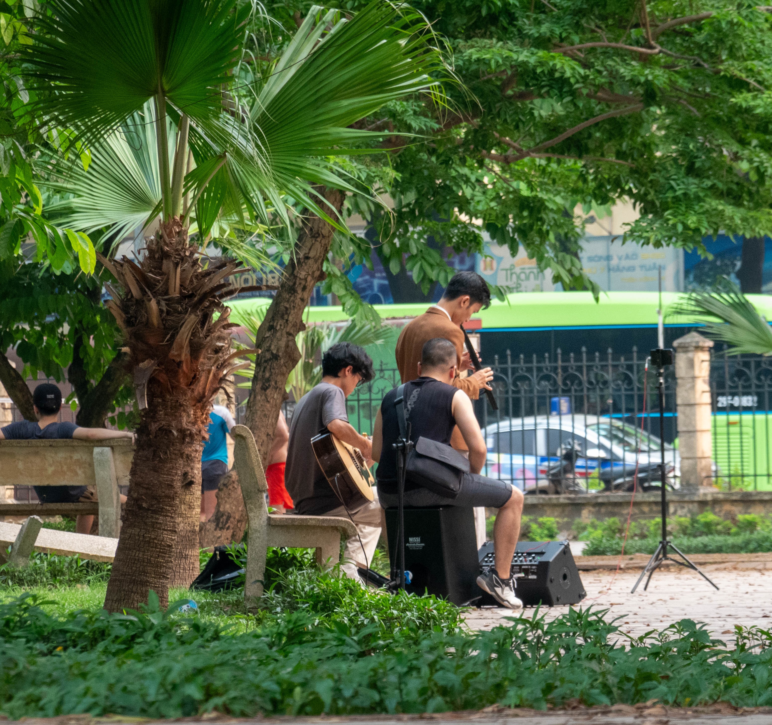 man playing guitar and man playing flute in park
