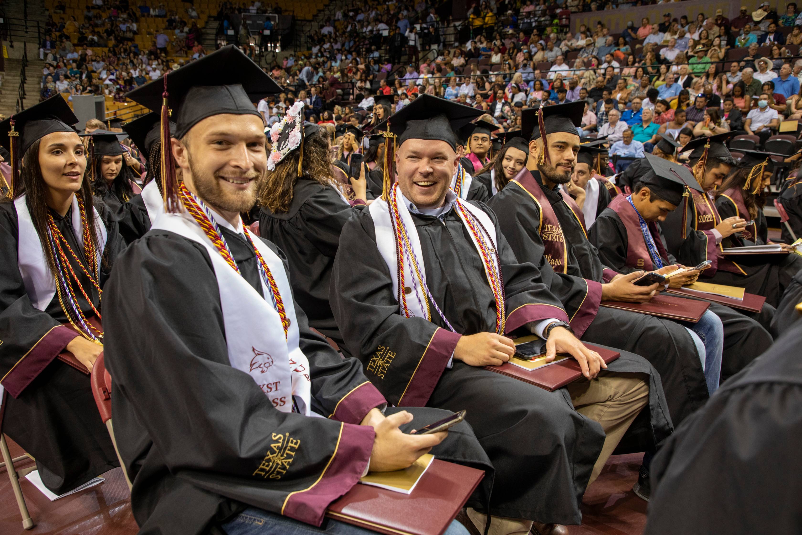 Graduates sitting and smiling during commencement