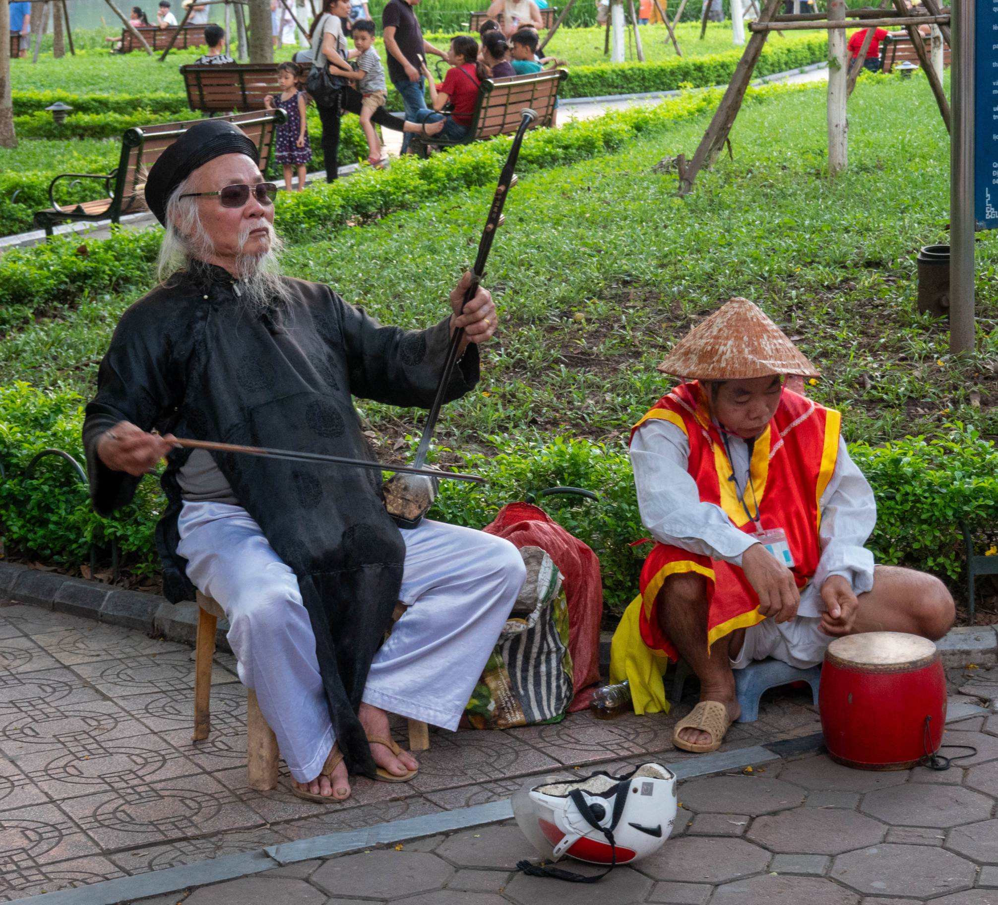 man playing taditional string instrument on left and man playing a traditional drum on right 