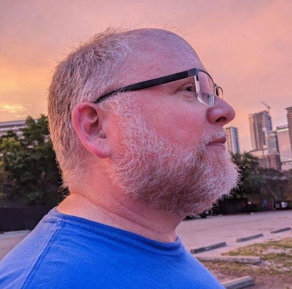 Man in profile wearing glasses and blue t-shirt, sunset 
