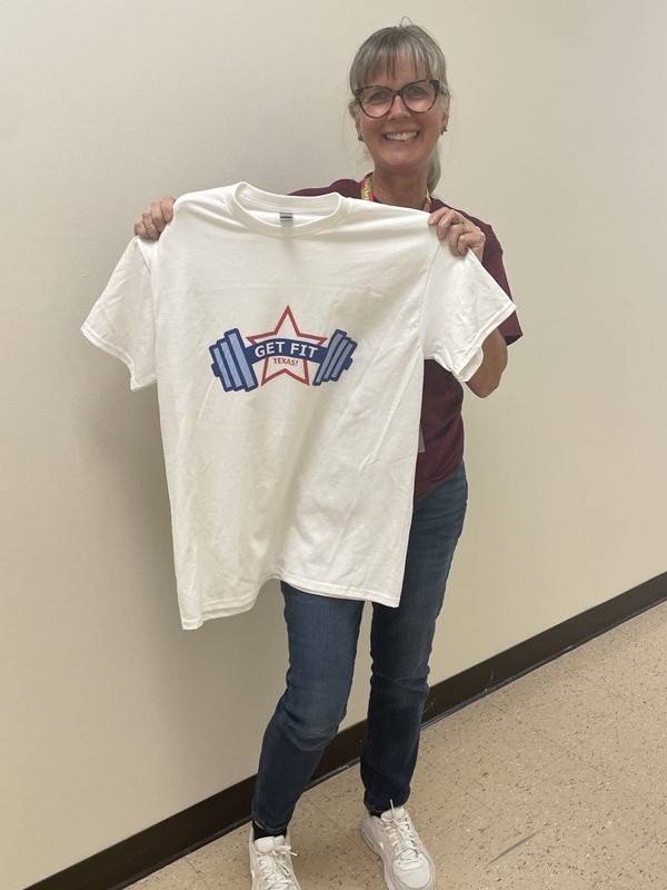 Photo of employee holding a Get Fit Texas t-shirt up to their body