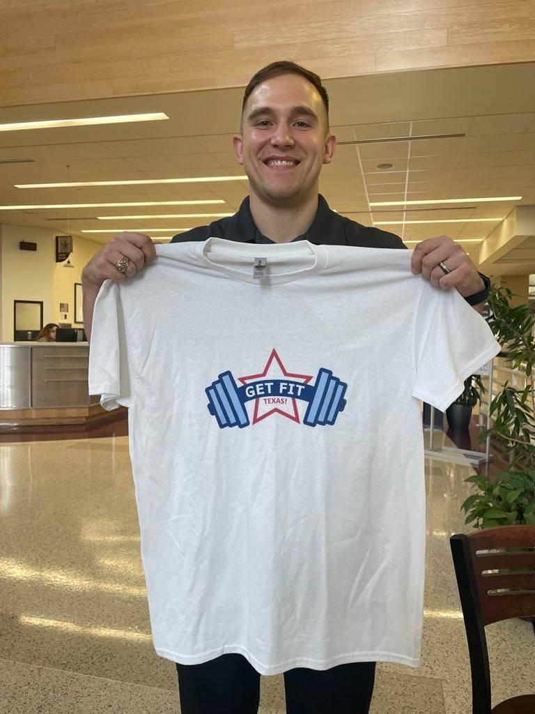 Photo of employee holding a Get Fit Texas t-shirt up to their body