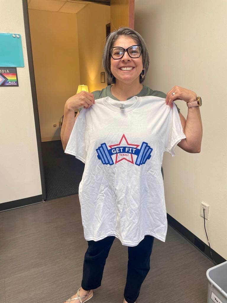 Photo of employee holding a Get Fit Texas t-shirt up to their body