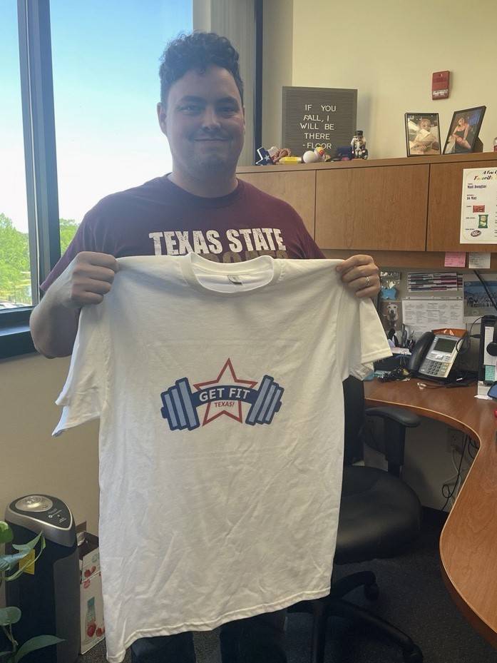 Photo of employee holding a Get Fit Texas t-shirt up to their body