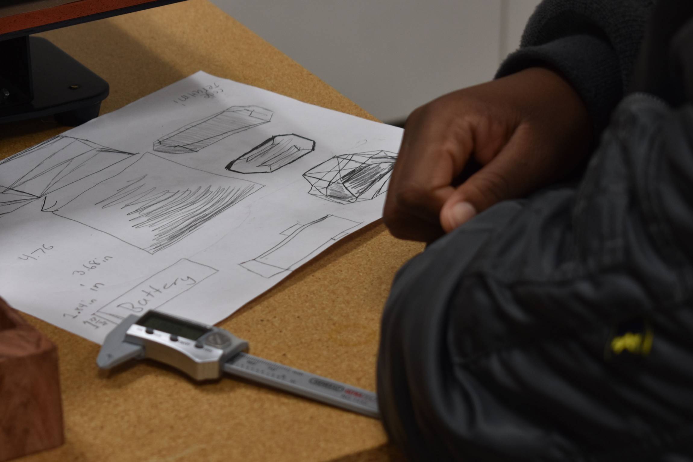 A NSBE Jr. student works on his design on paper before making adjustments in the computer
