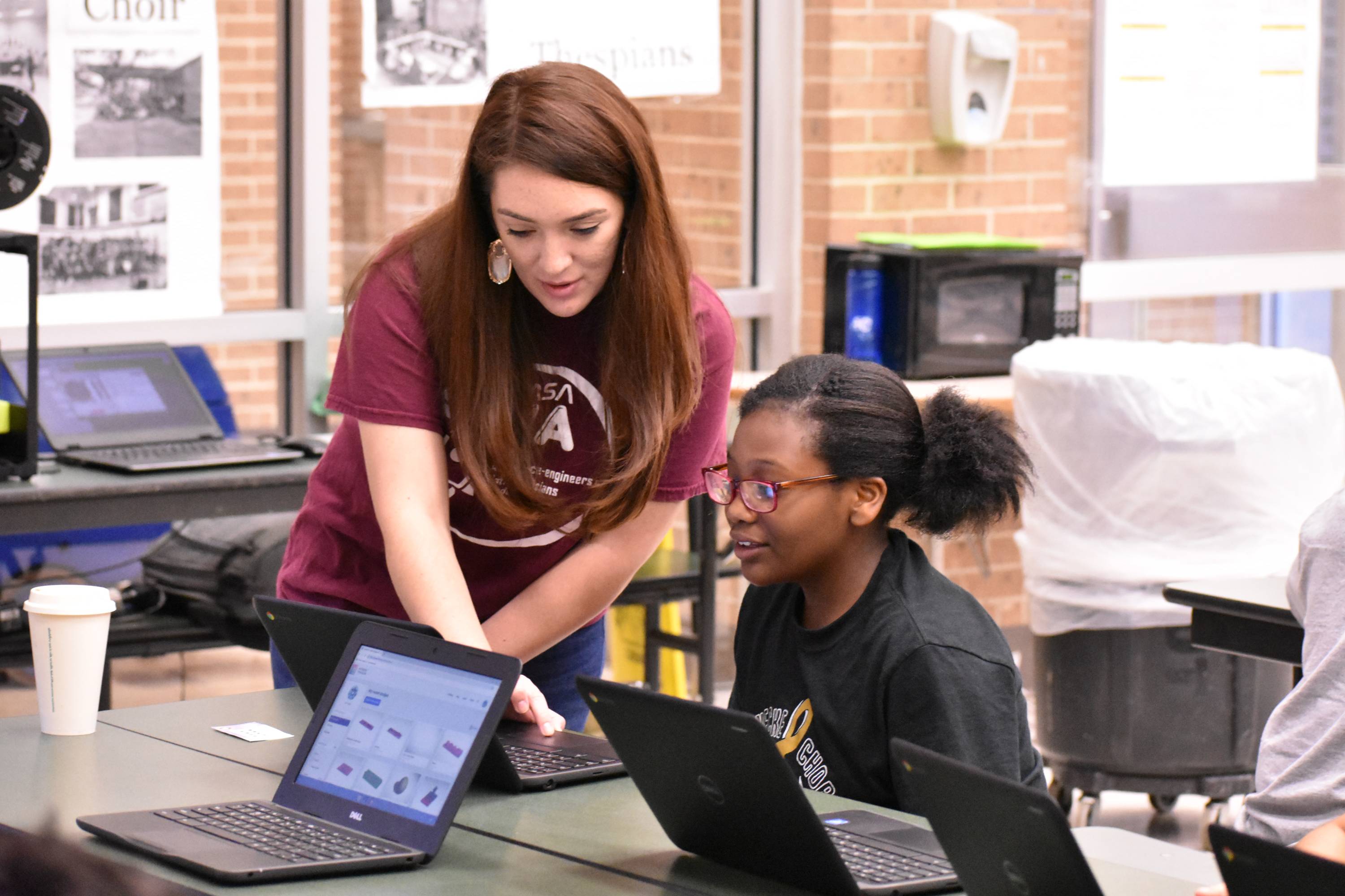 a Texas State student helps a child with her 3D printing project on her computer