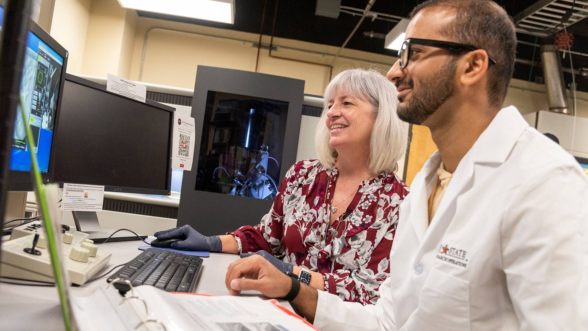 Faculty member and student looking at computer in research lab