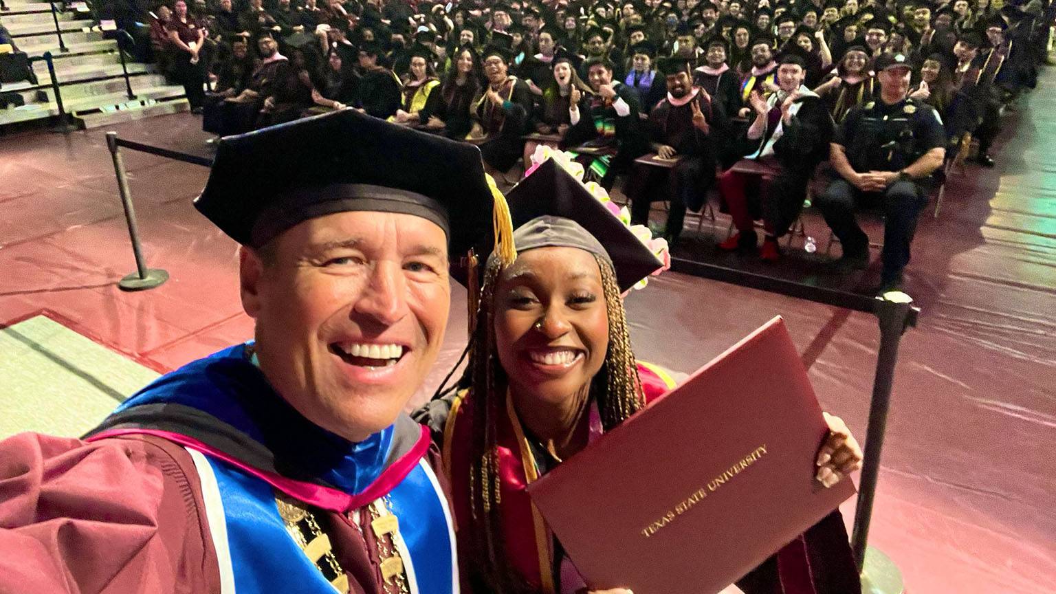 President Damphousse (left) poses for a photo with a new TXST graduate at commencement.