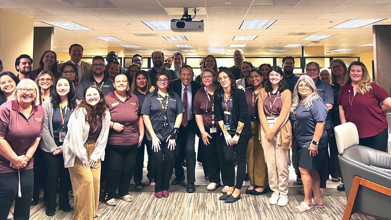 President Damphousse poses for a photo with a large group of financial aid staff members.