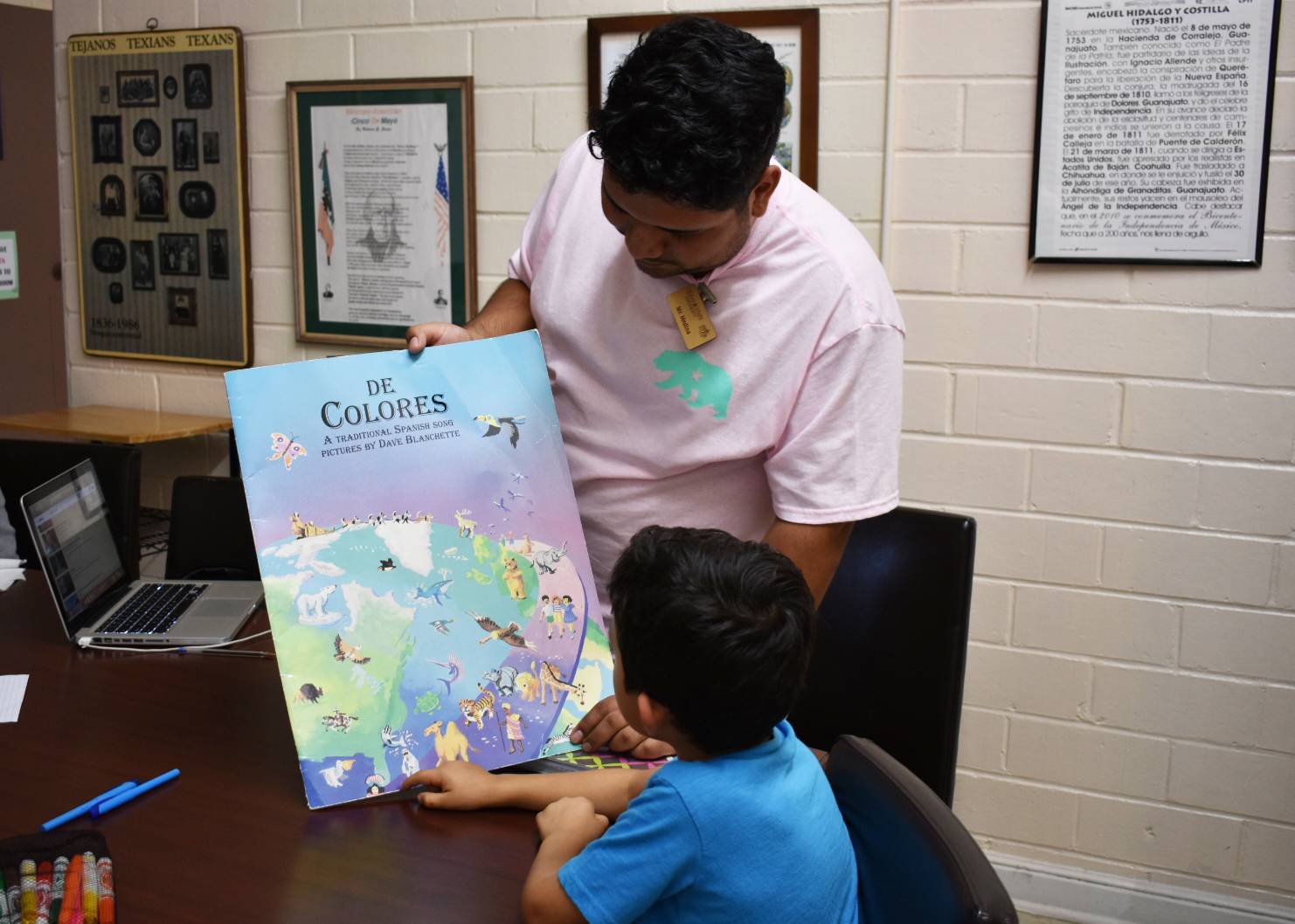 Bilingual/Bilcultural Education student Jacob Medina presents a book to one of the SMCISD students.