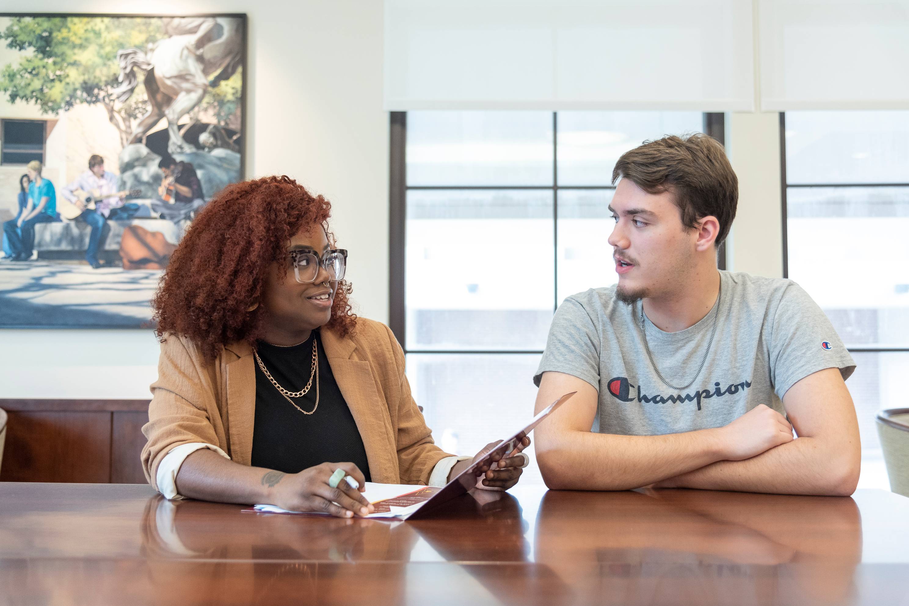 two students talking while sitting at a table