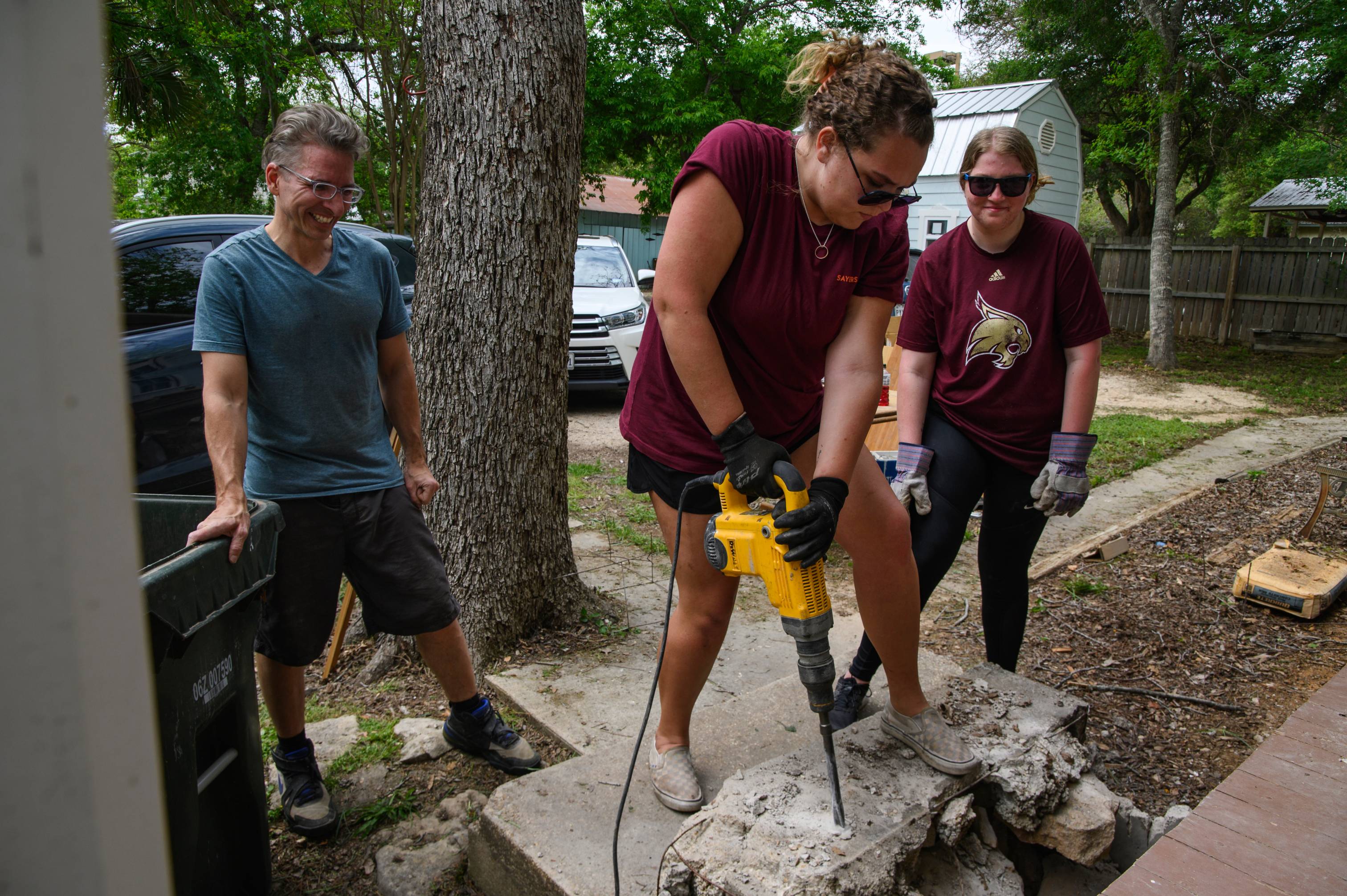 Students volunteering by participating in Bobcat Build. They are drilling into concrete. 