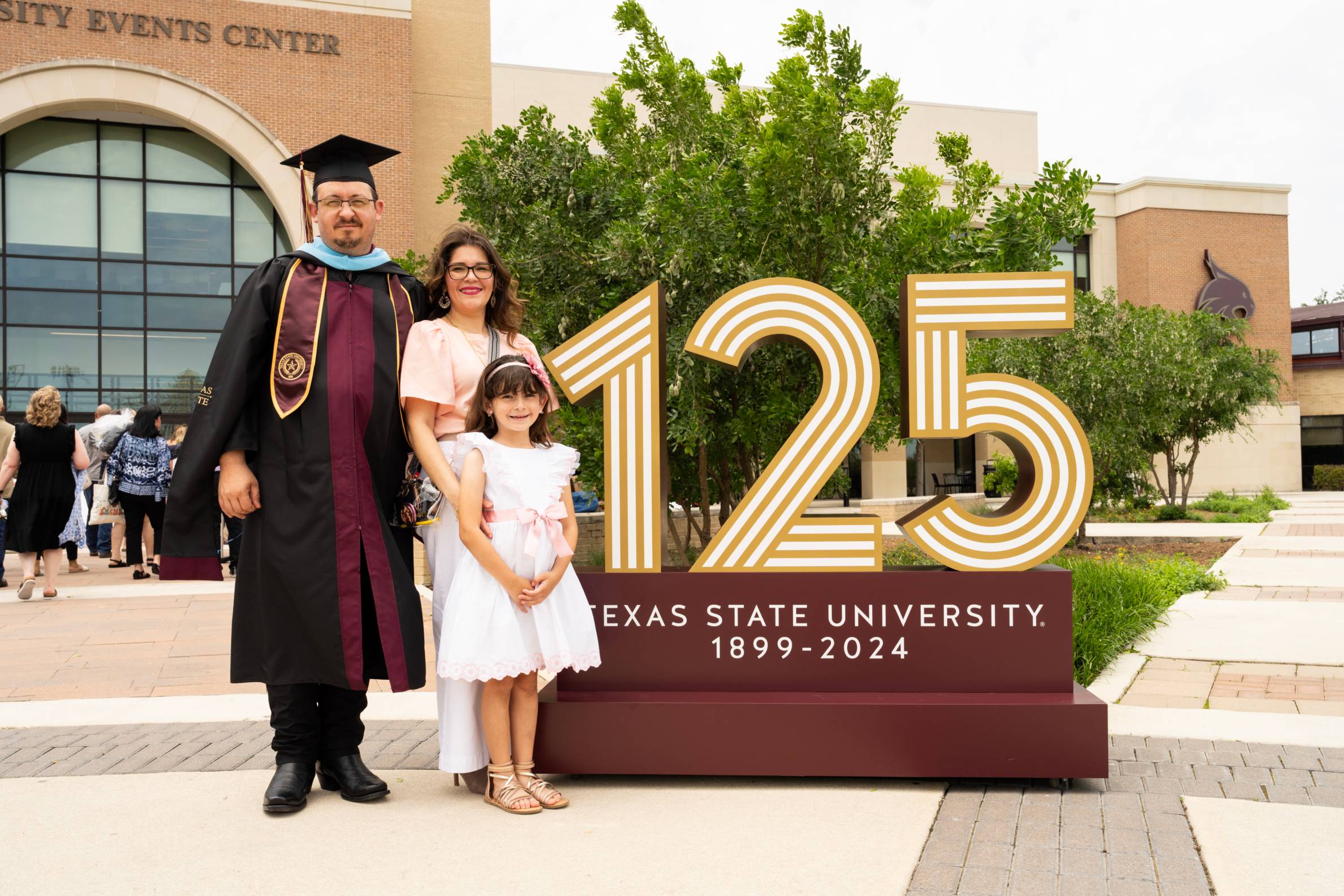 A graduate and their family smile and pose