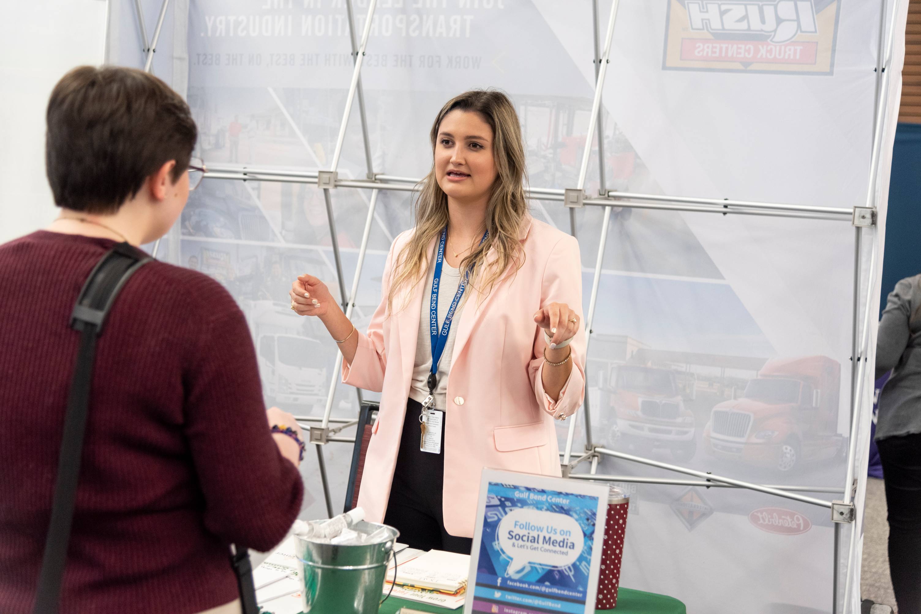 A recruiters speaking to a student at a career fair booth
