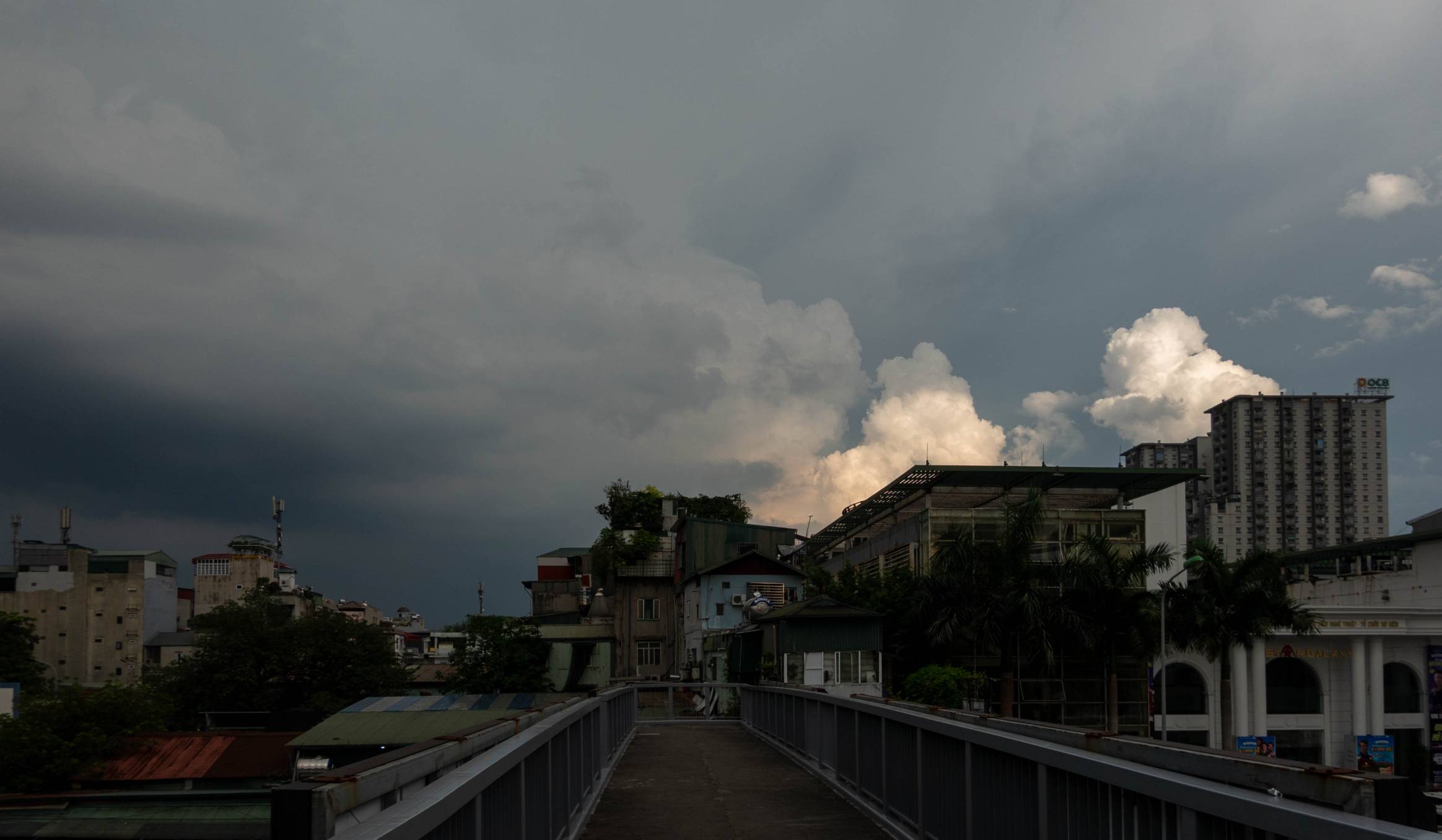 photo of dark rain clouds on left of photo with white cumulus clouds reflecting sunlight.