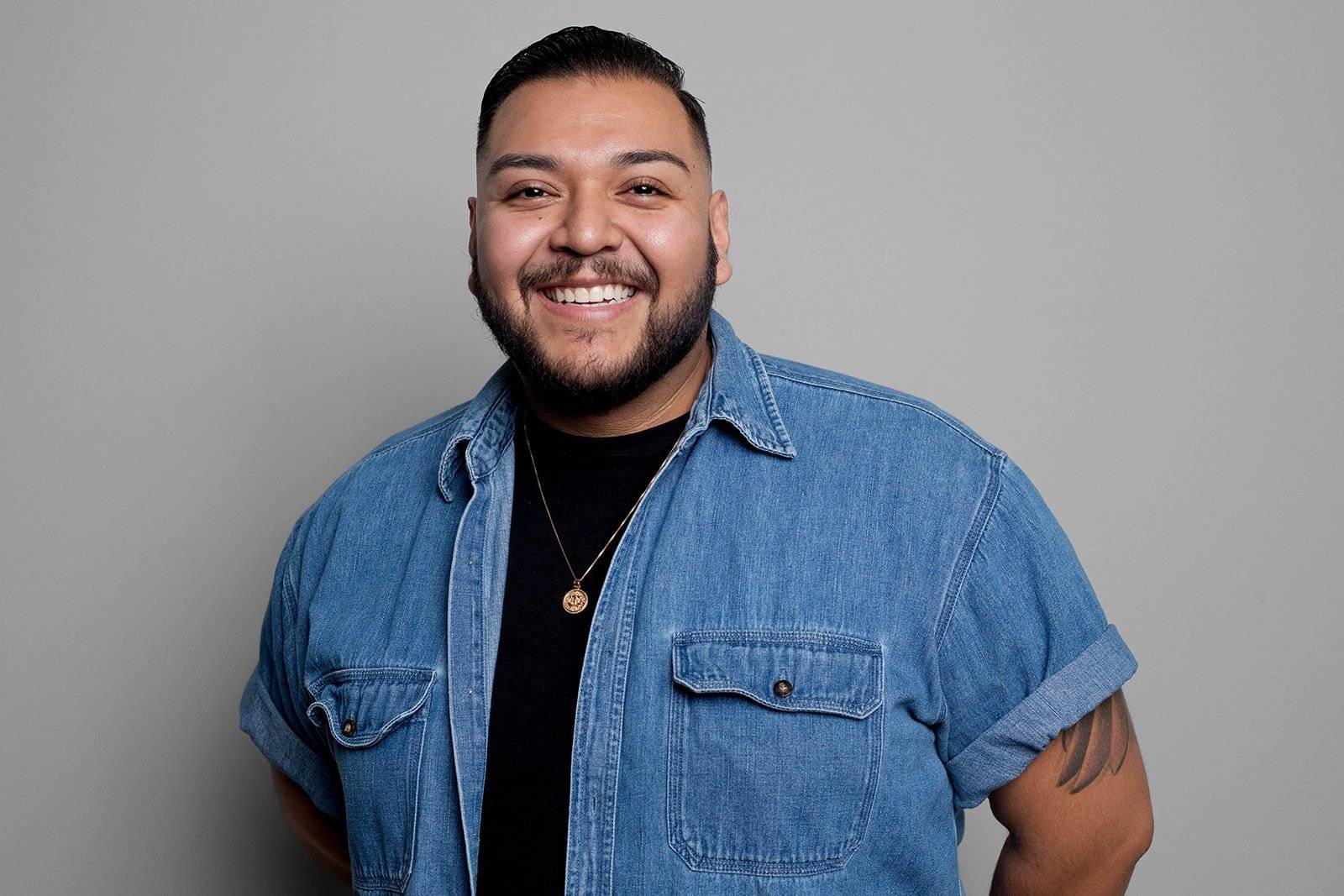 Saul Hernandez in front of a blank background smiling