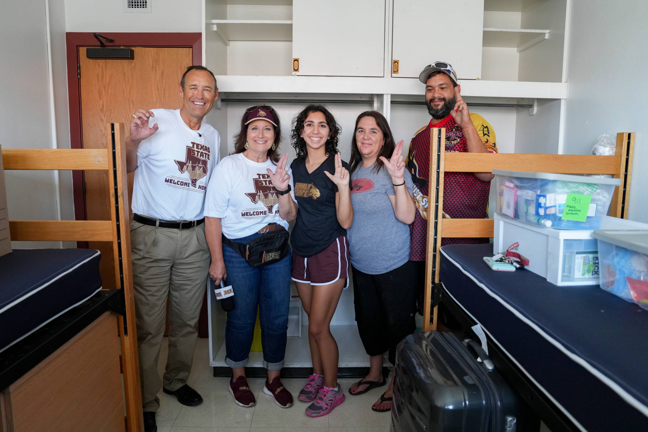 people standing and smiling in a dorm room 