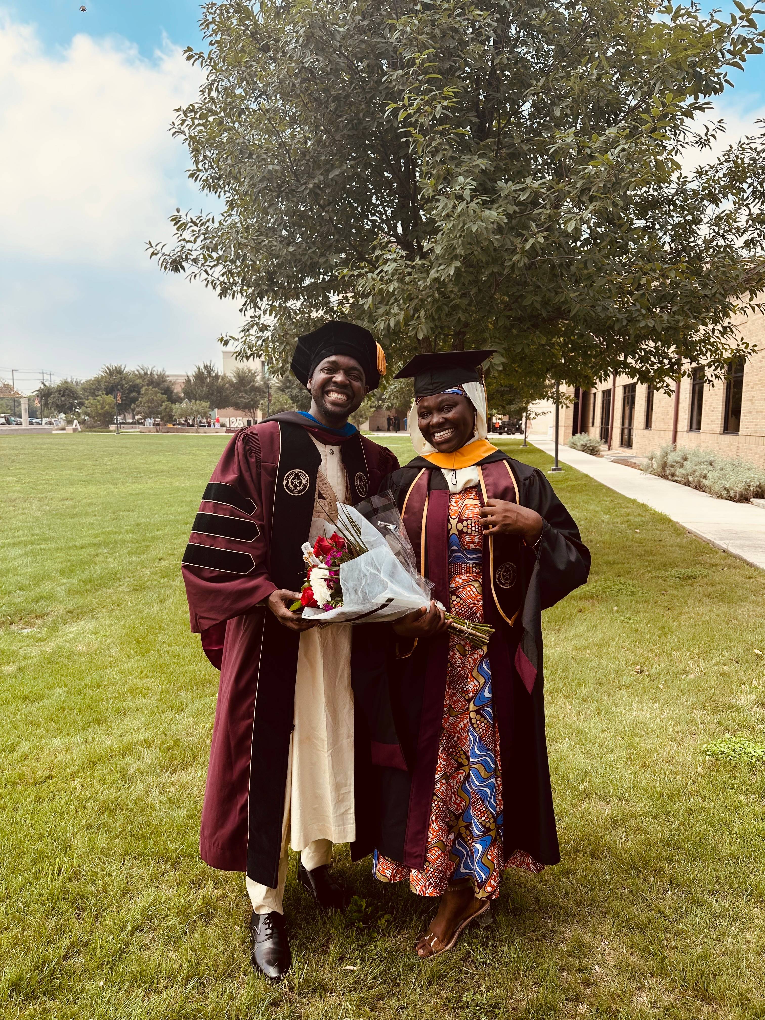 two graduates standing outside in a field