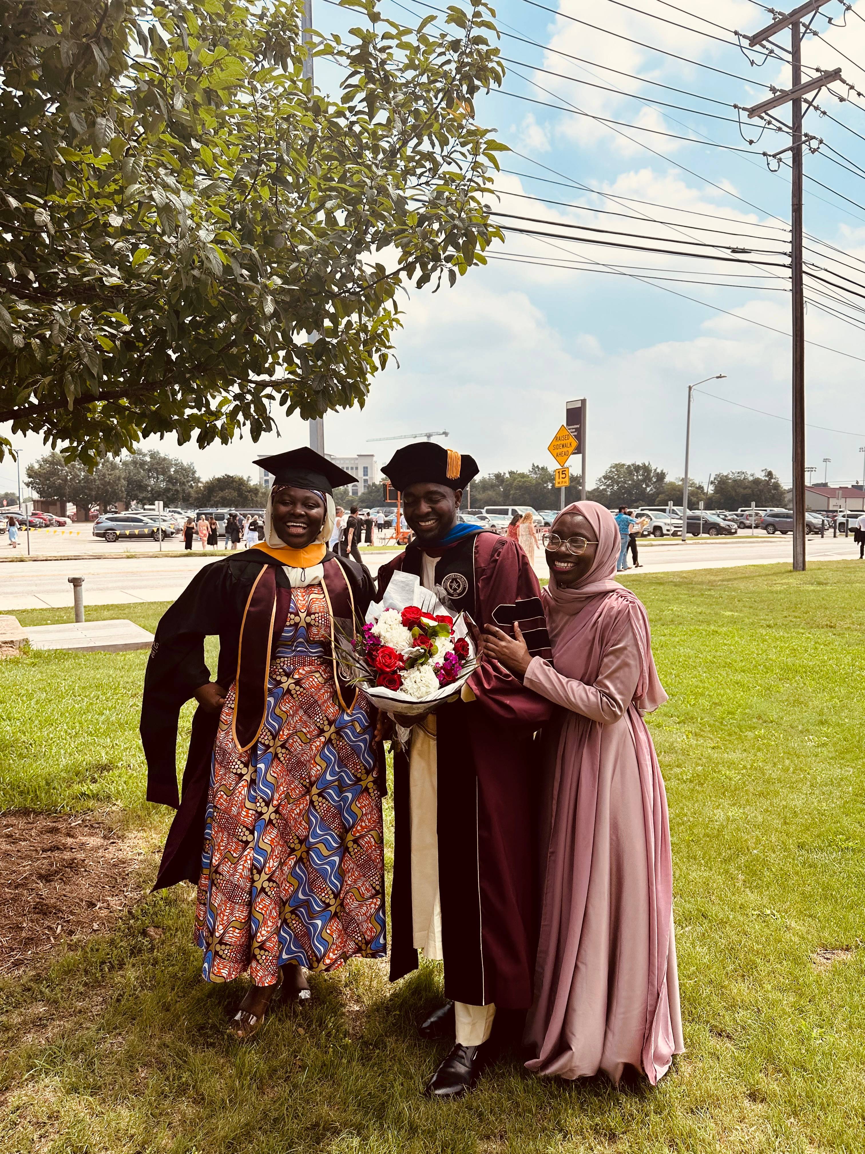 graduates pose with family members in a field