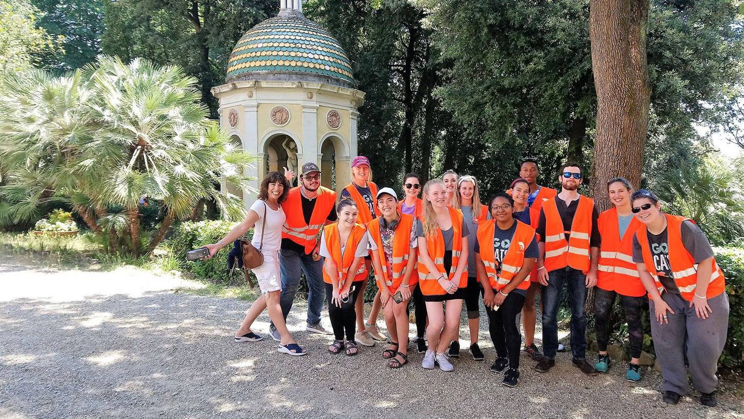group of students wearing orange safety vests, trees, gazebo