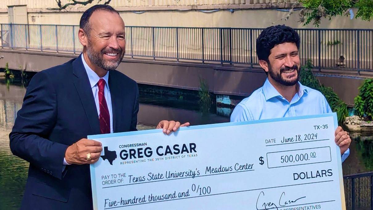 President Damphousse (left) poses for a photo Congressman Greg Casar and large check.