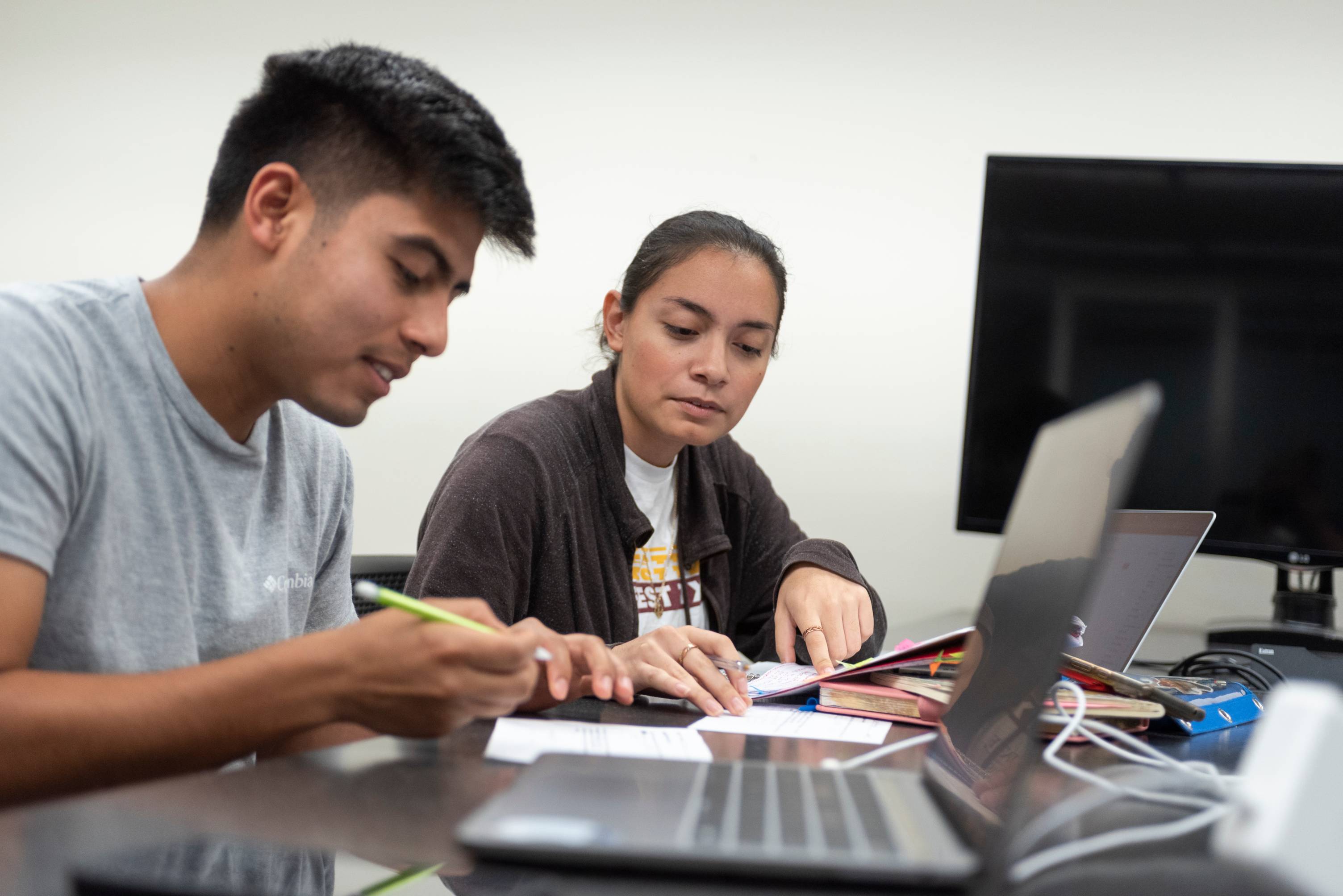 Female Graduate Student assisting a male student with homework.