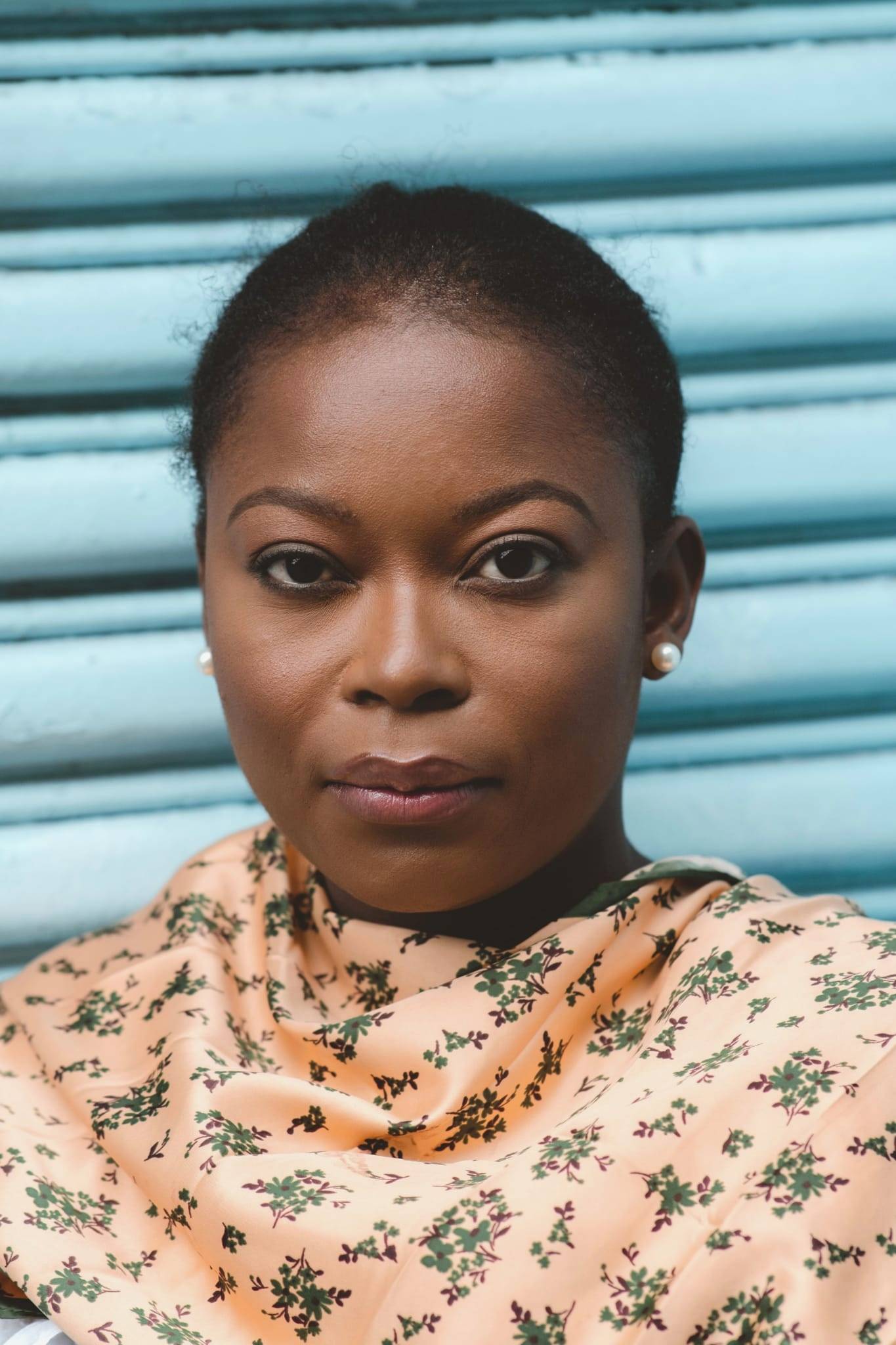 Nithy Kasa in front of a blue corrugated piece of metal 