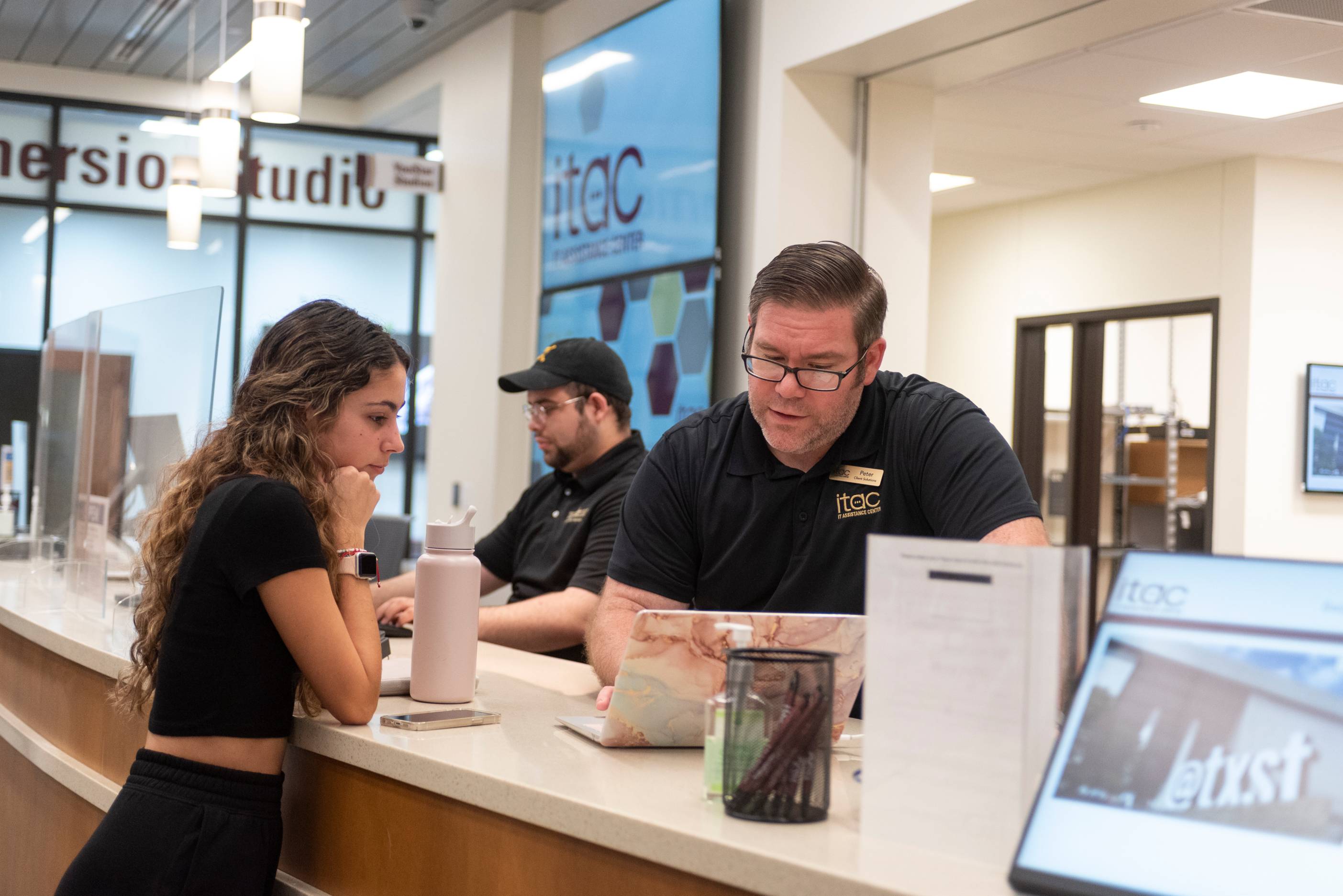 Service Center employee assisting a student with her laptop.