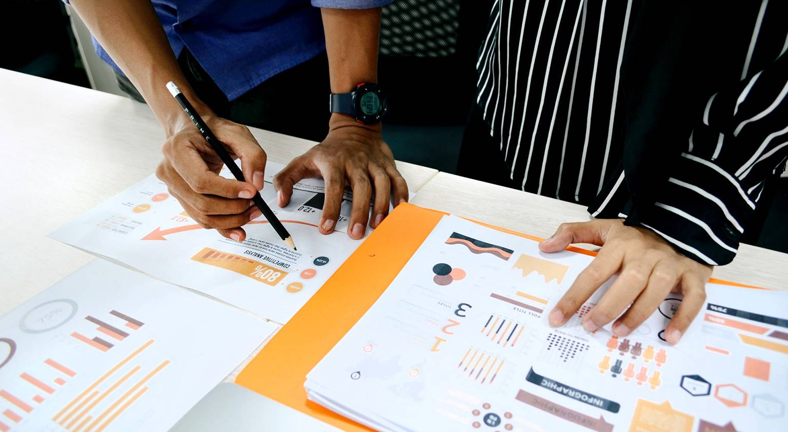 A downward view of two people looking at data charts.