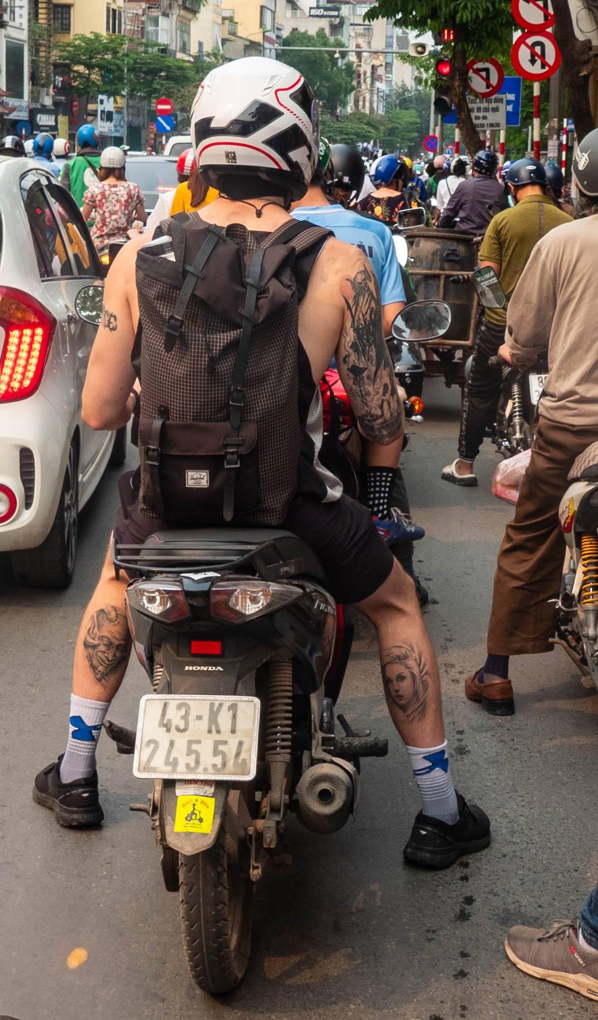 picture of motorbike passenger with face tattoos on the back of their calves.