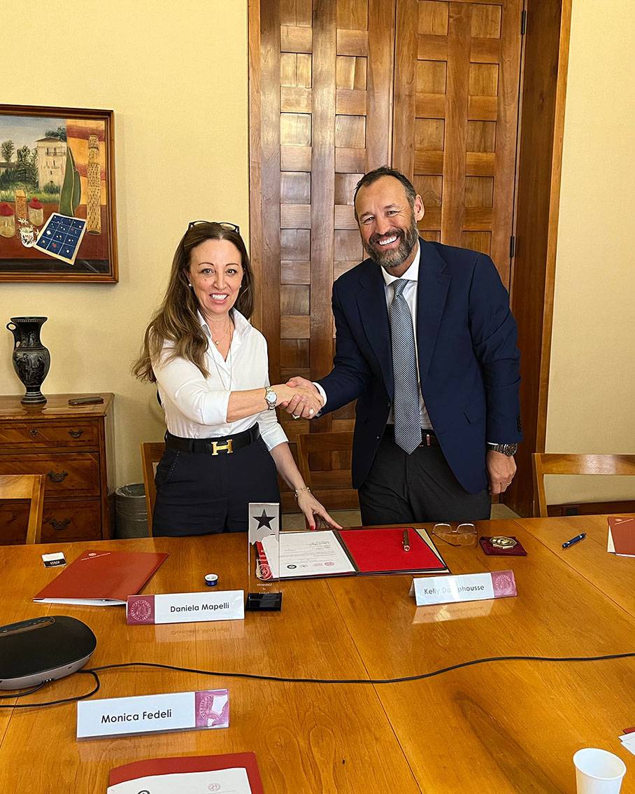 Dr. Daniela Mapelli (left) shakes the hand of TXST President Kelly Damphousse at a signing ceremony.