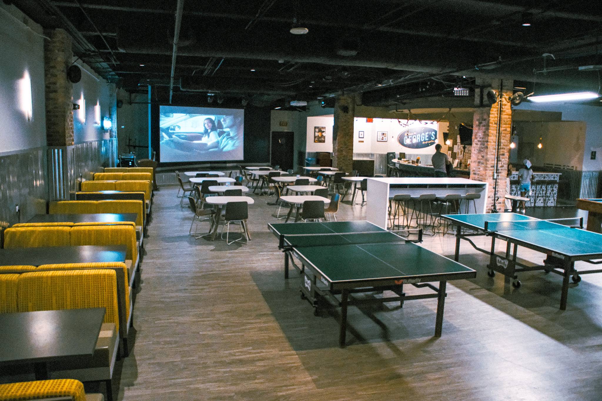 A room of tables and chairs and a projection screen