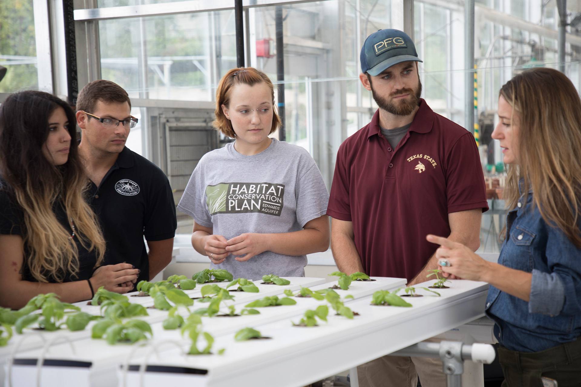 Students listening to professor in the greenhouse